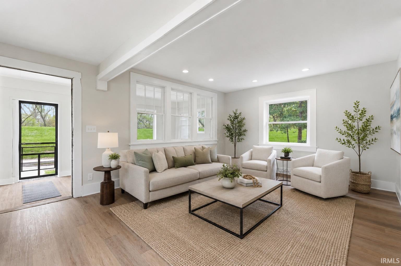 Bright living room featuring recessed lighting, wood-finish flooring, white trim, and multiple windows