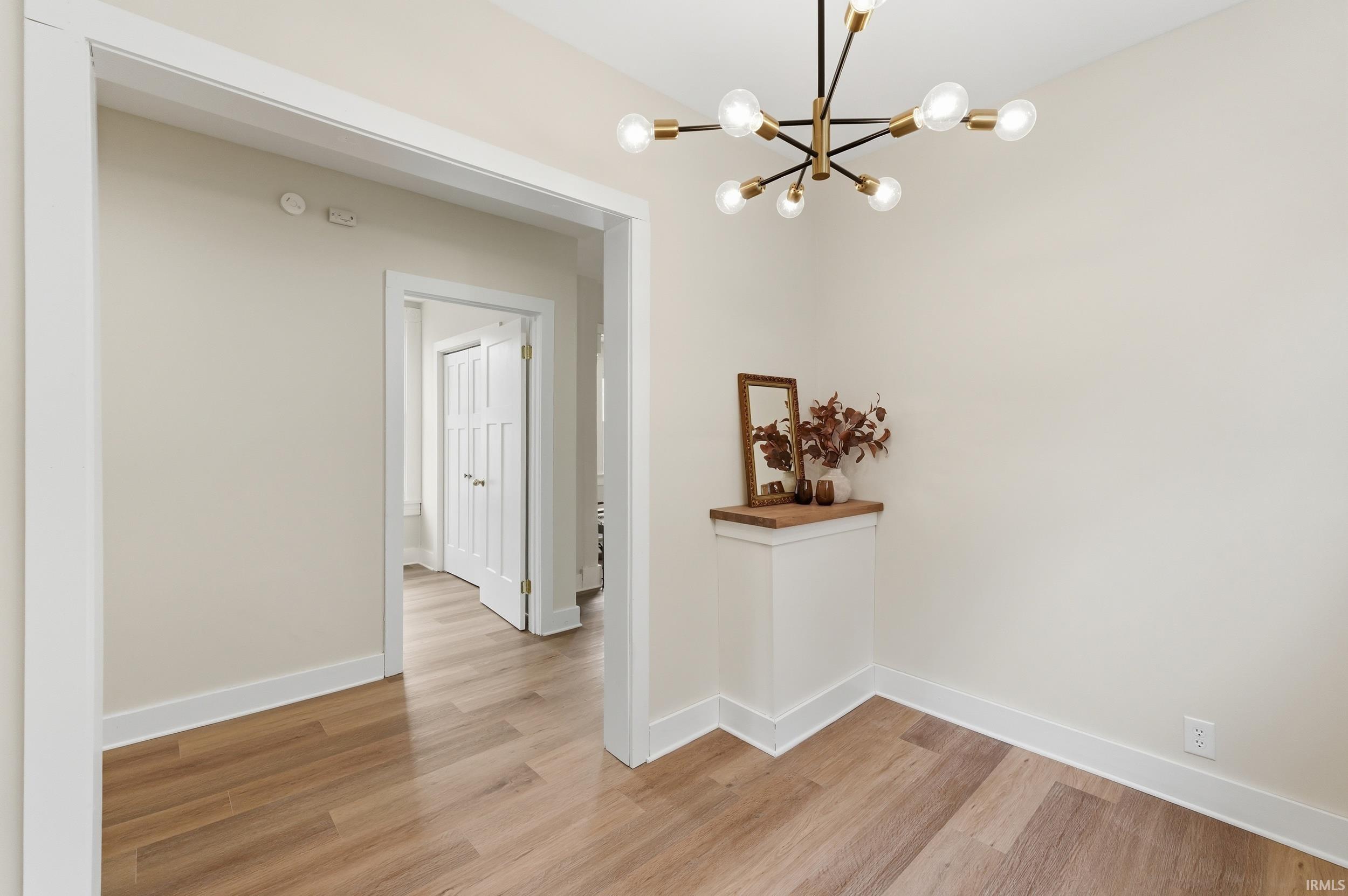 Corridor featuring hanging lights and light wood finished floors