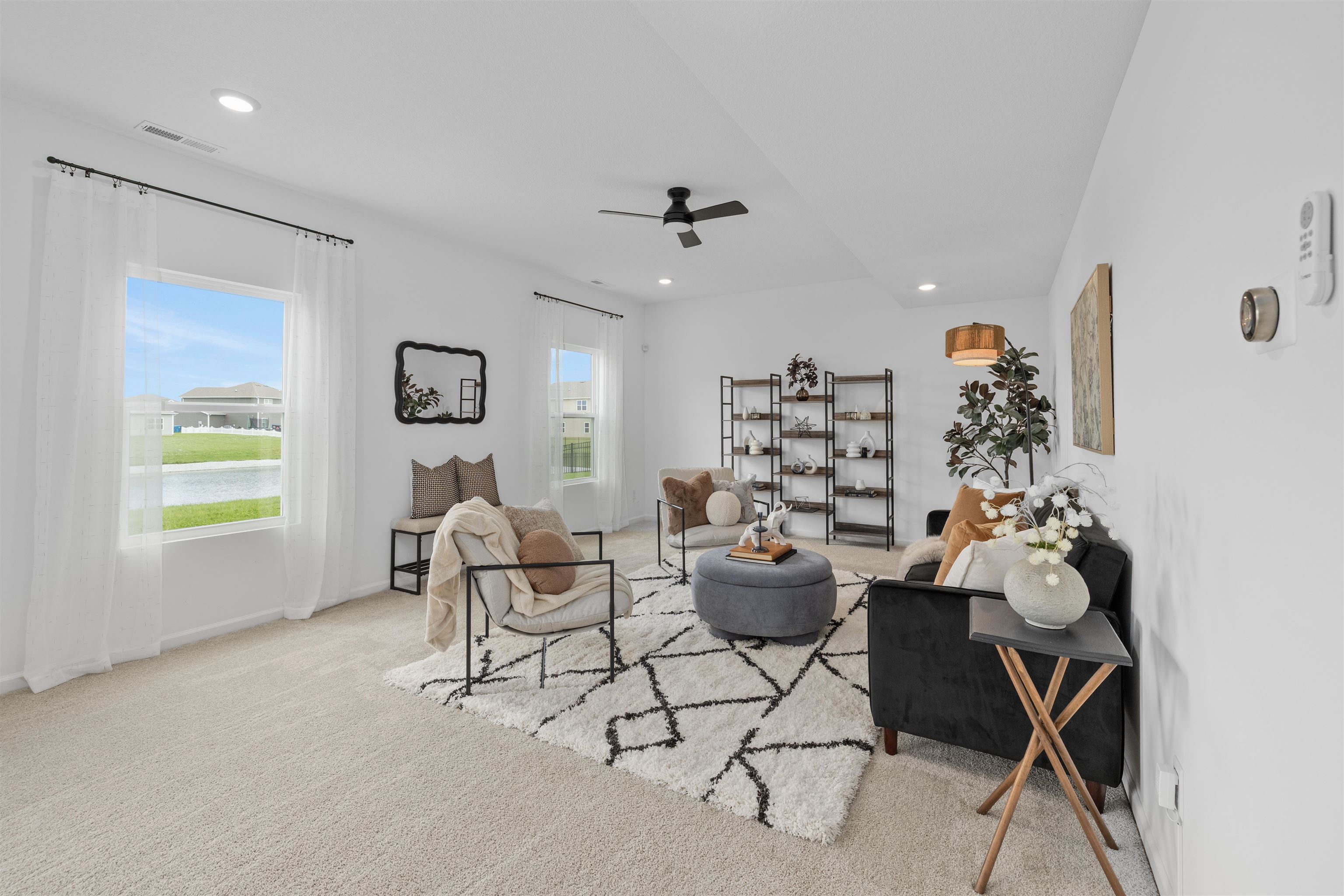 Carpeted living area featuring white walls, recessed lighting, and a contemporary ceiling fan