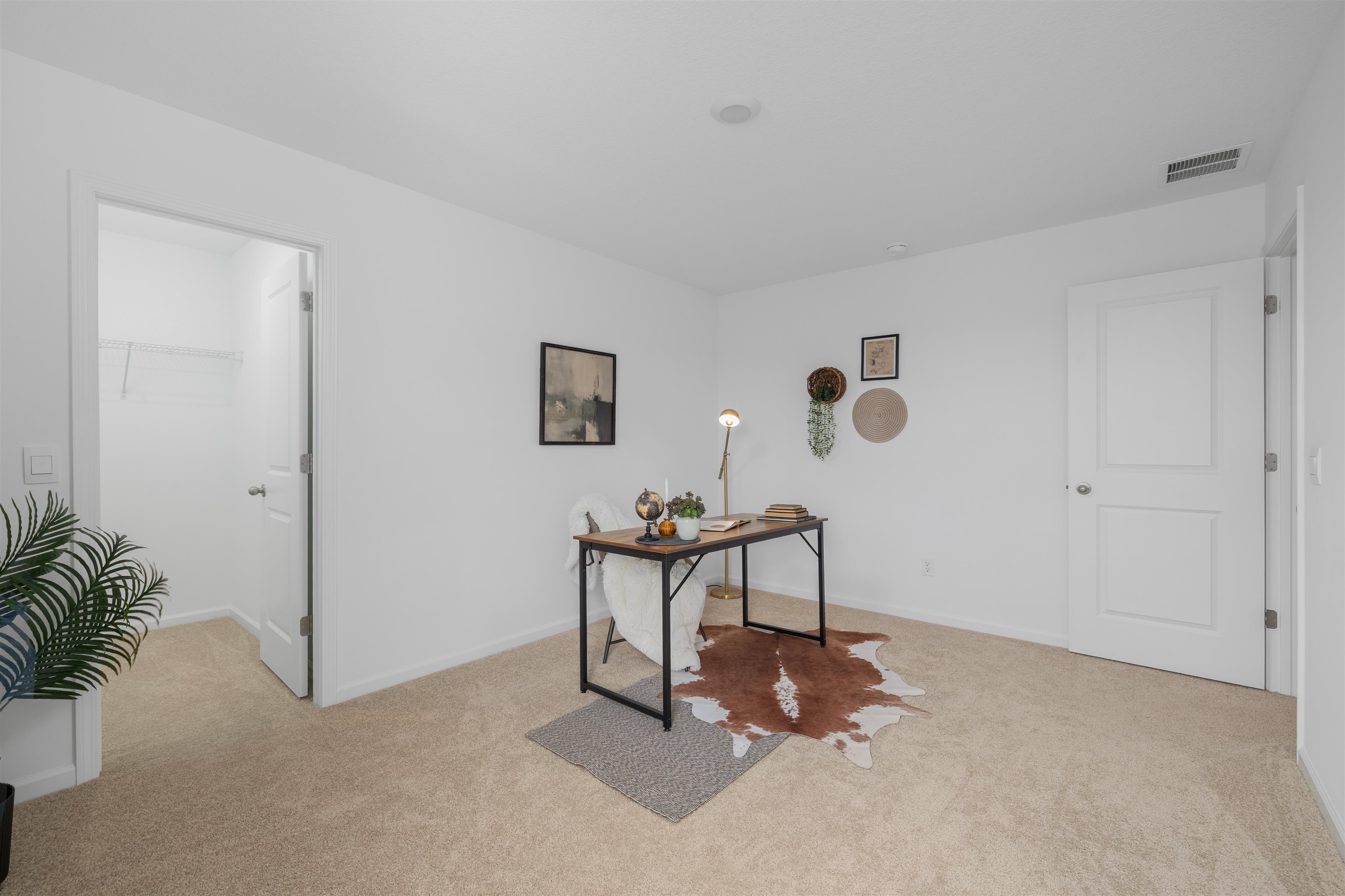 Carpeted room with white walls, featuring a standard two-panel interior door and a recessed light fixture