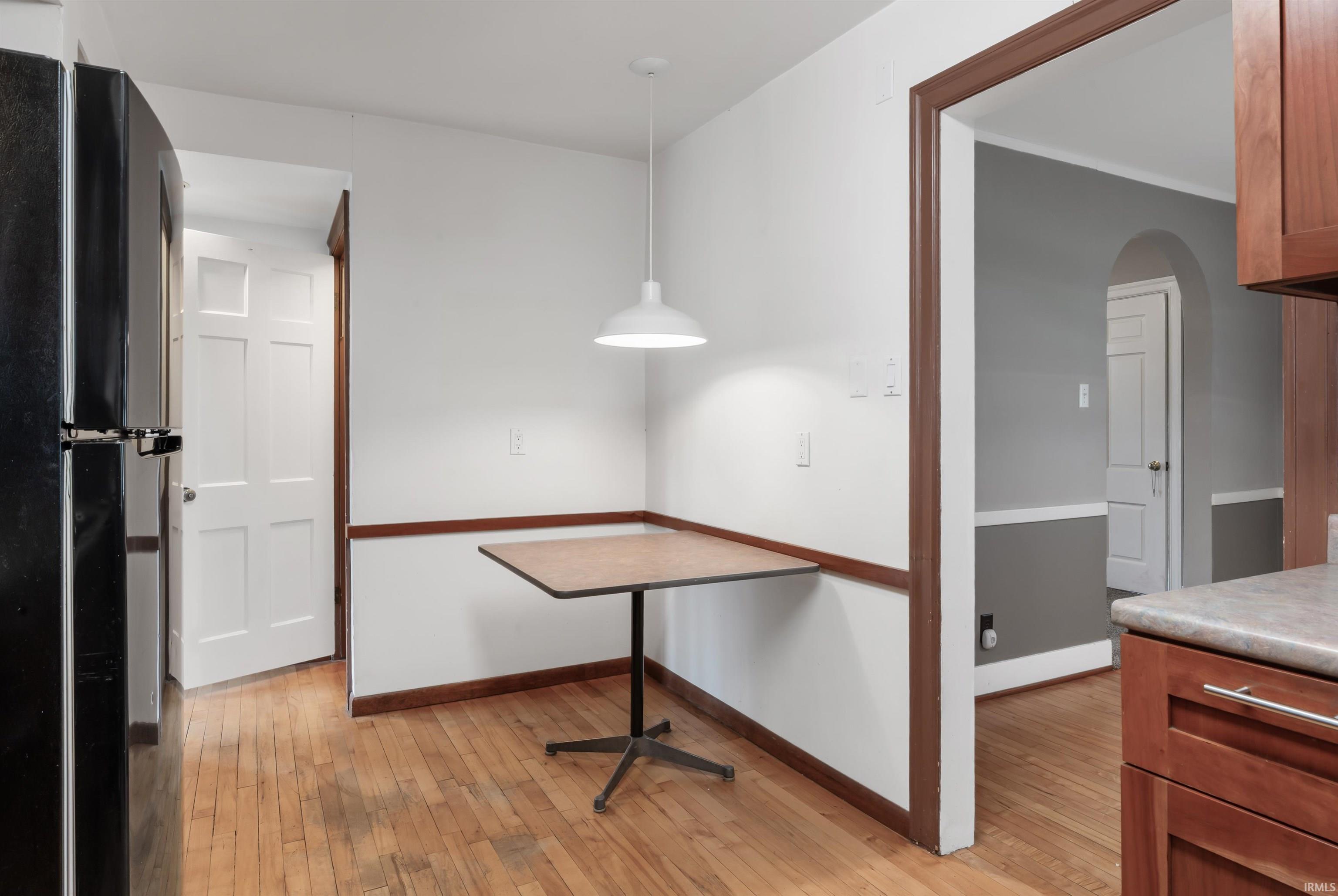 Unfurnished dining area featuring arched walkways and light wood-type flooring