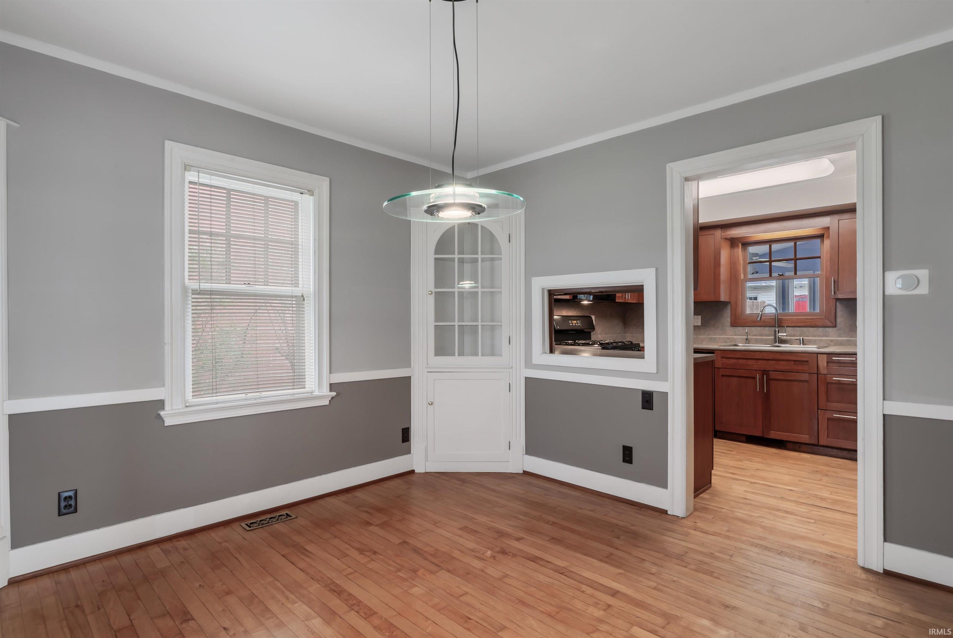 Unfurnished dining area featuring light wood-type flooring and ornamental molding