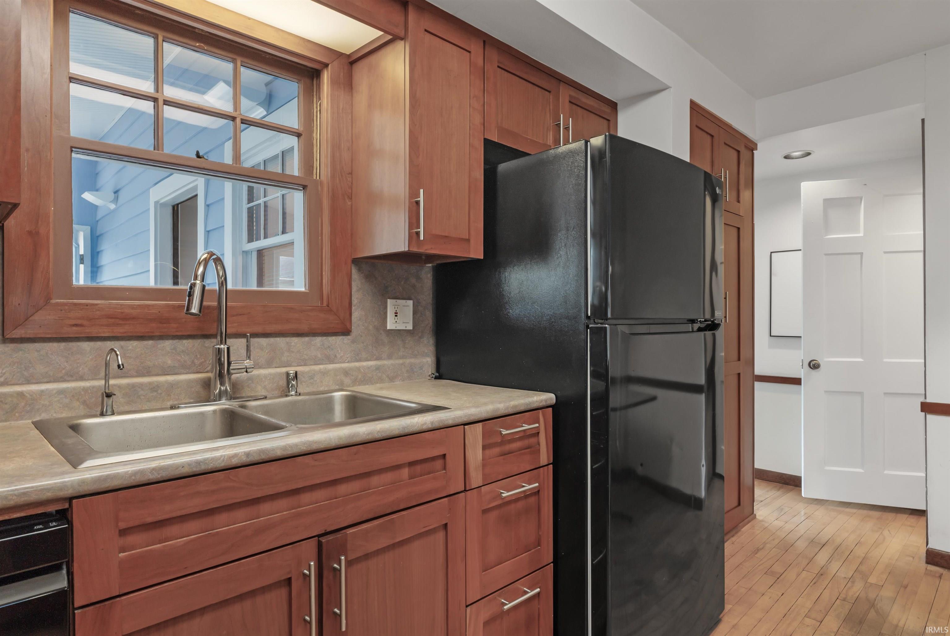 Kitchen featuring wood finish cabinets, light countertops, freestanding refrigerator, and light wood-style flooring