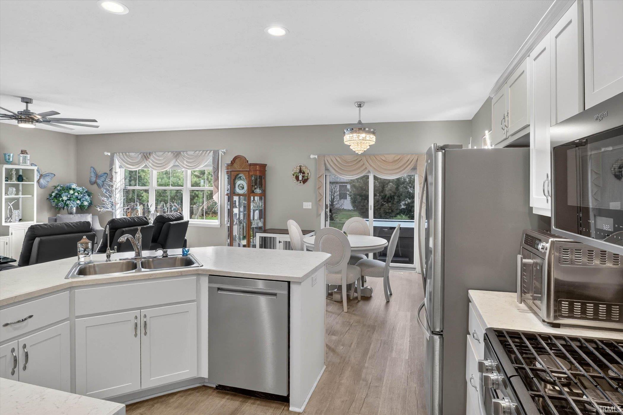 Kitchen with white cabinetry, light countertops, stainless steel appliances, and light wood-type flooring