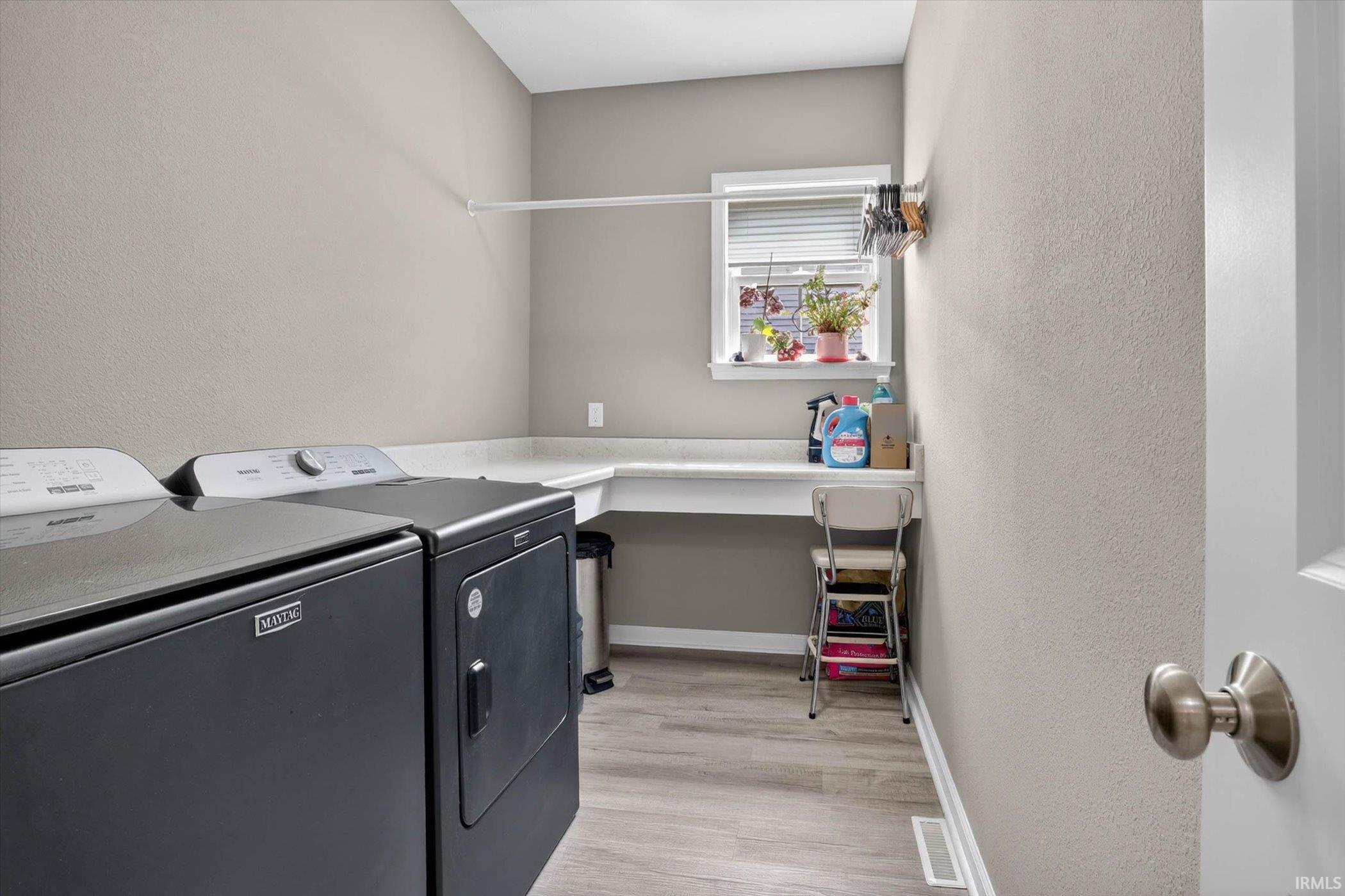 Laundry room with an office area, a textured wall, light wood-style floors, and washing machine and dryer