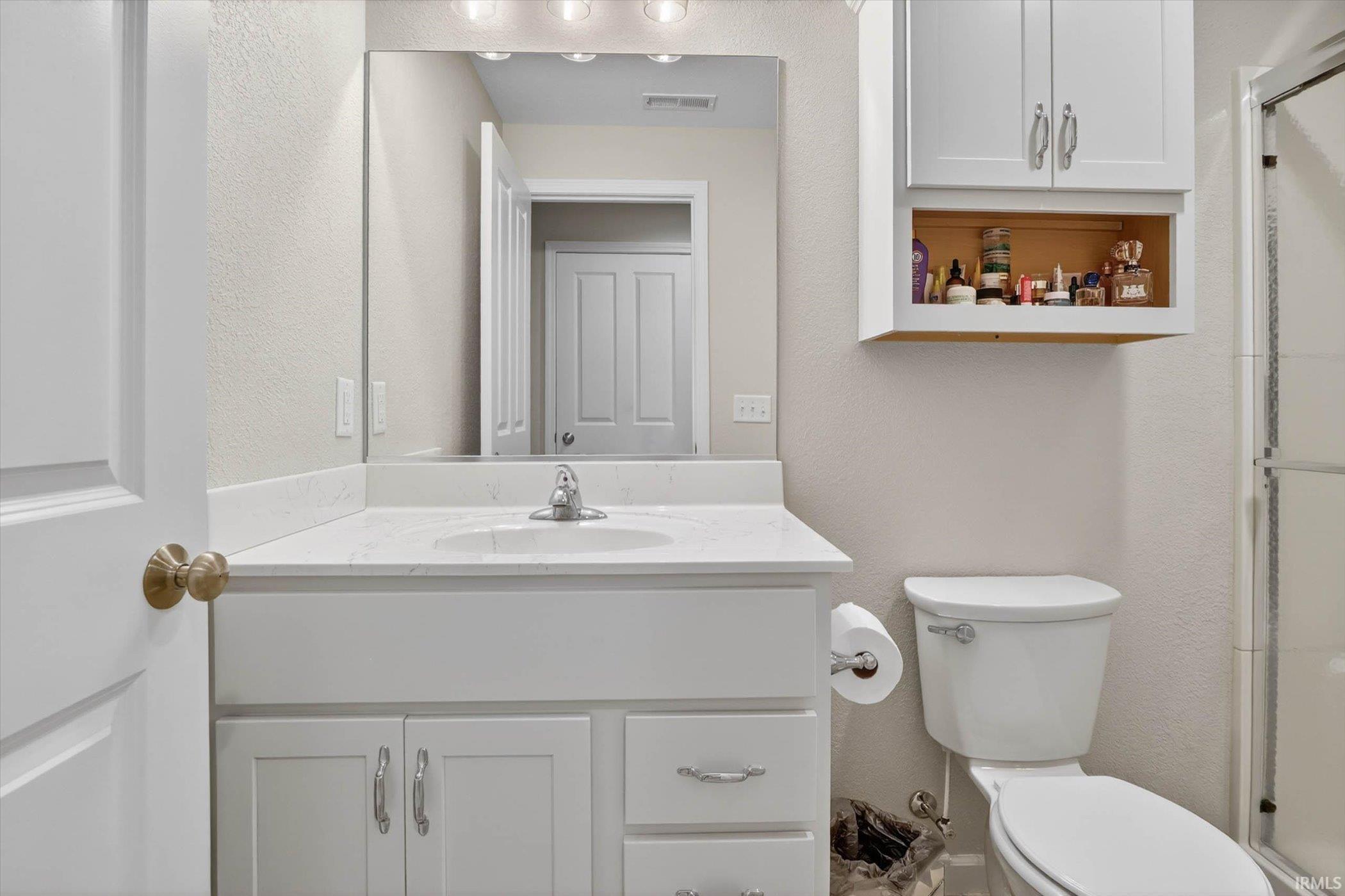 Full bathroom with a stall shower, vanity, and a textured wall