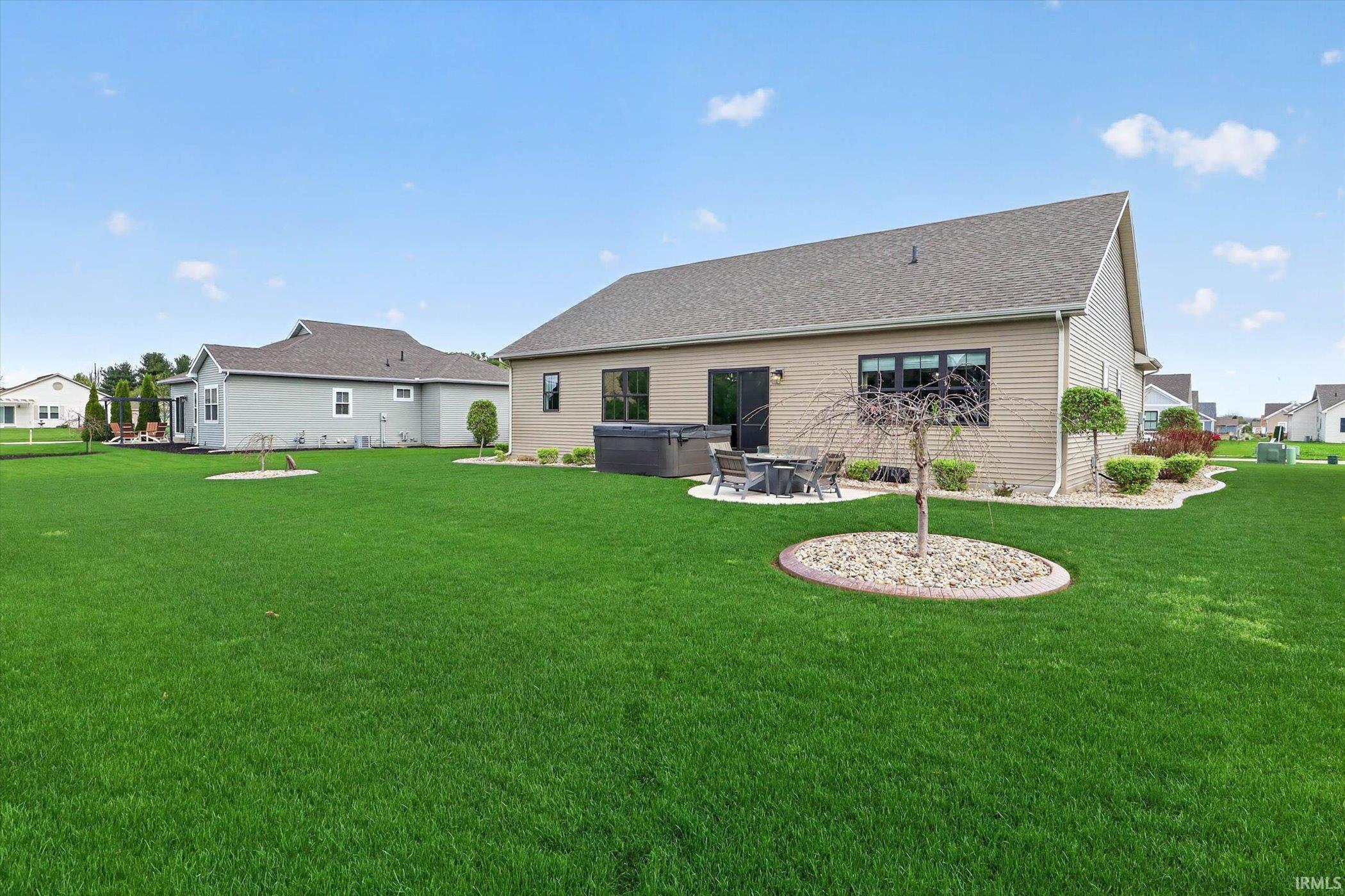 Rear view of house with a patio, a hot tub, a yard, and roof with shingles