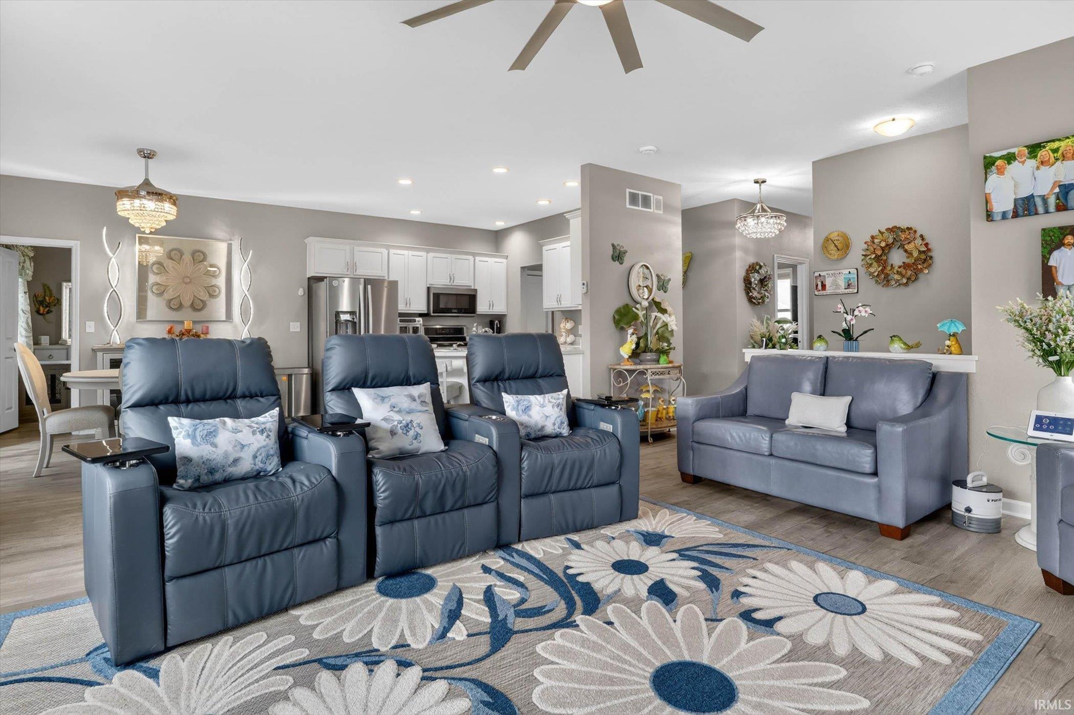 Living room featuring suspended lighting, light wood finished floors, and ceiling fan