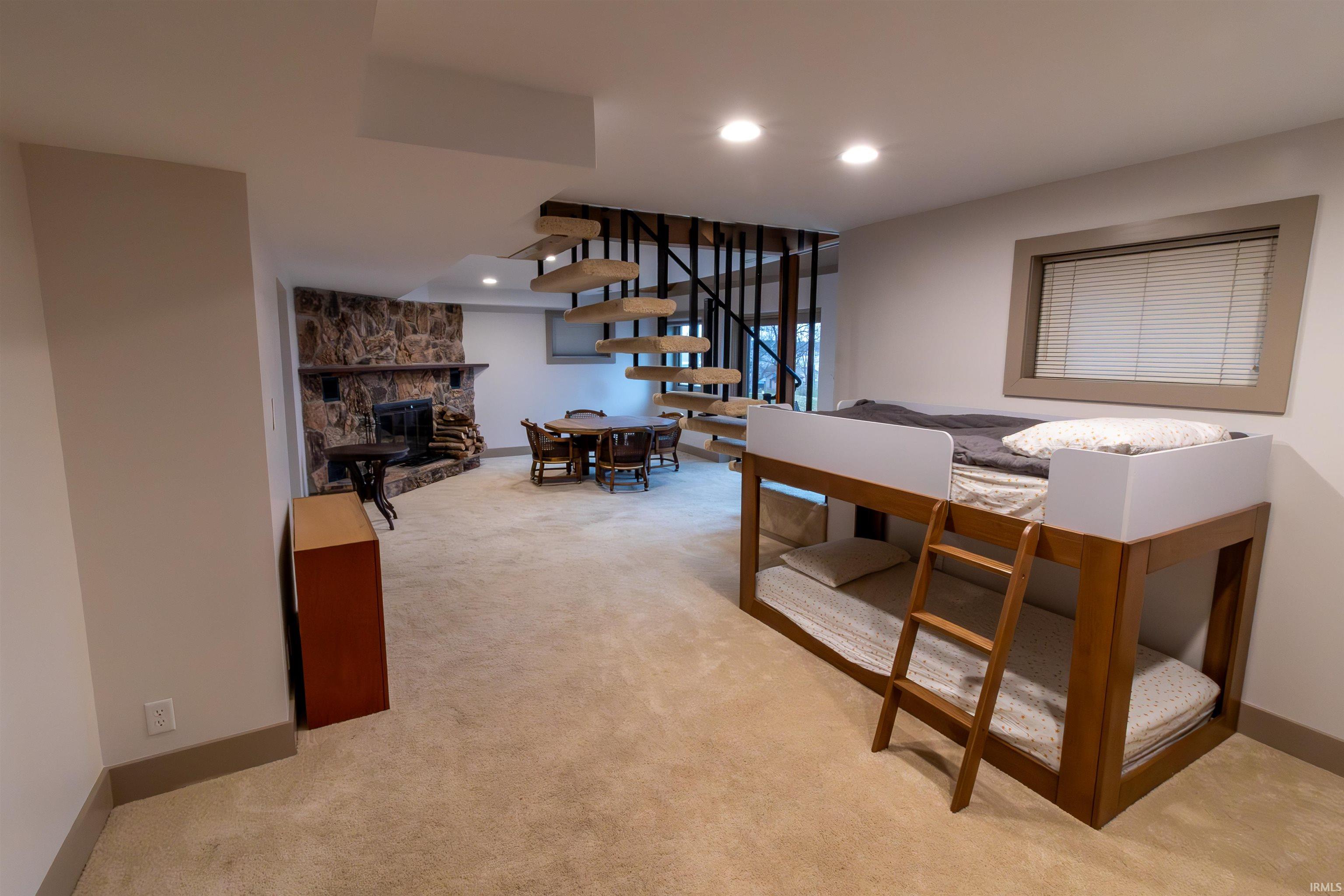 Basement living area with a stone fireplace, light carpet, and recessed lighting