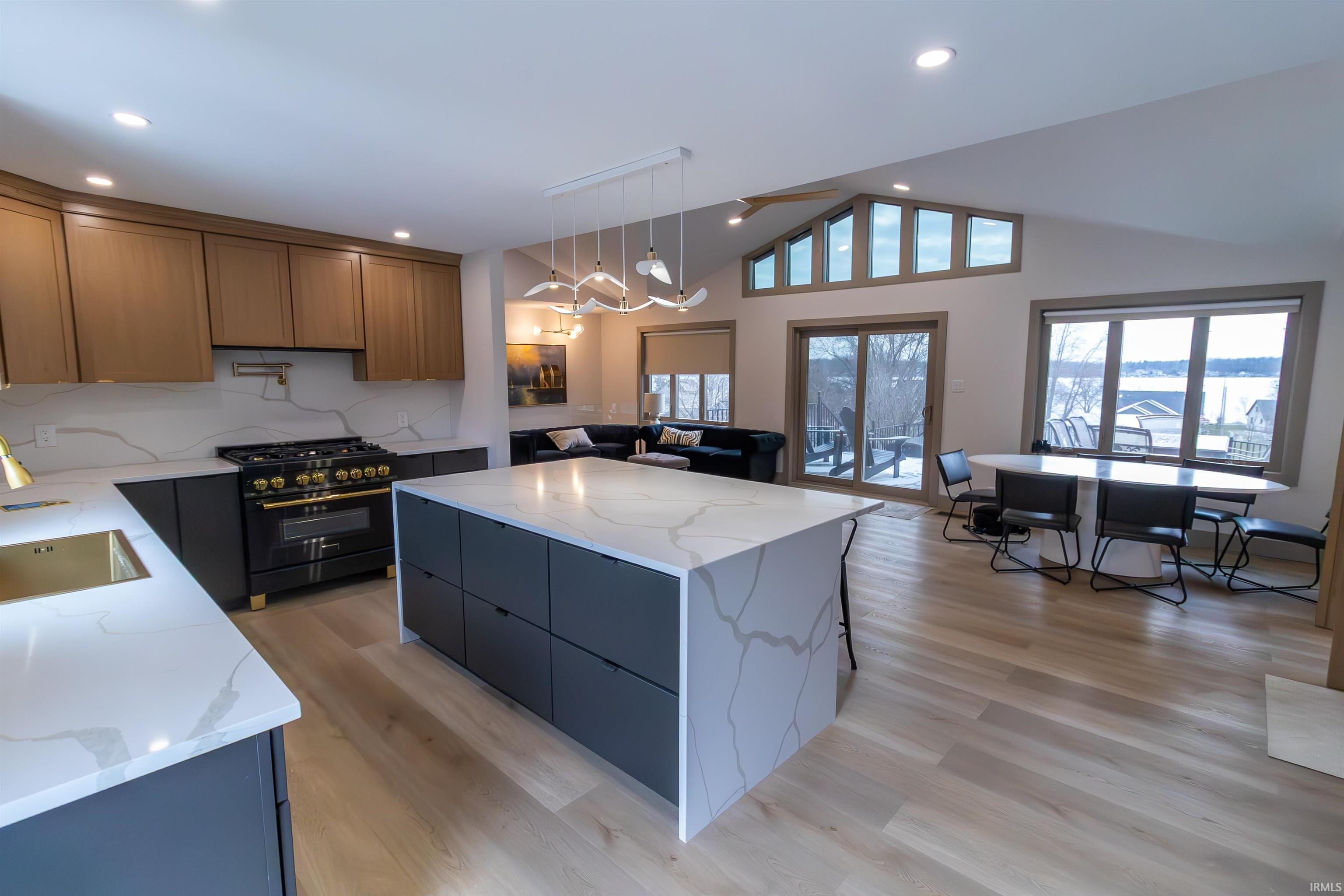 Kitchen with light stone countertops, a kitchen island, high end black range oven, and vaulted ceiling