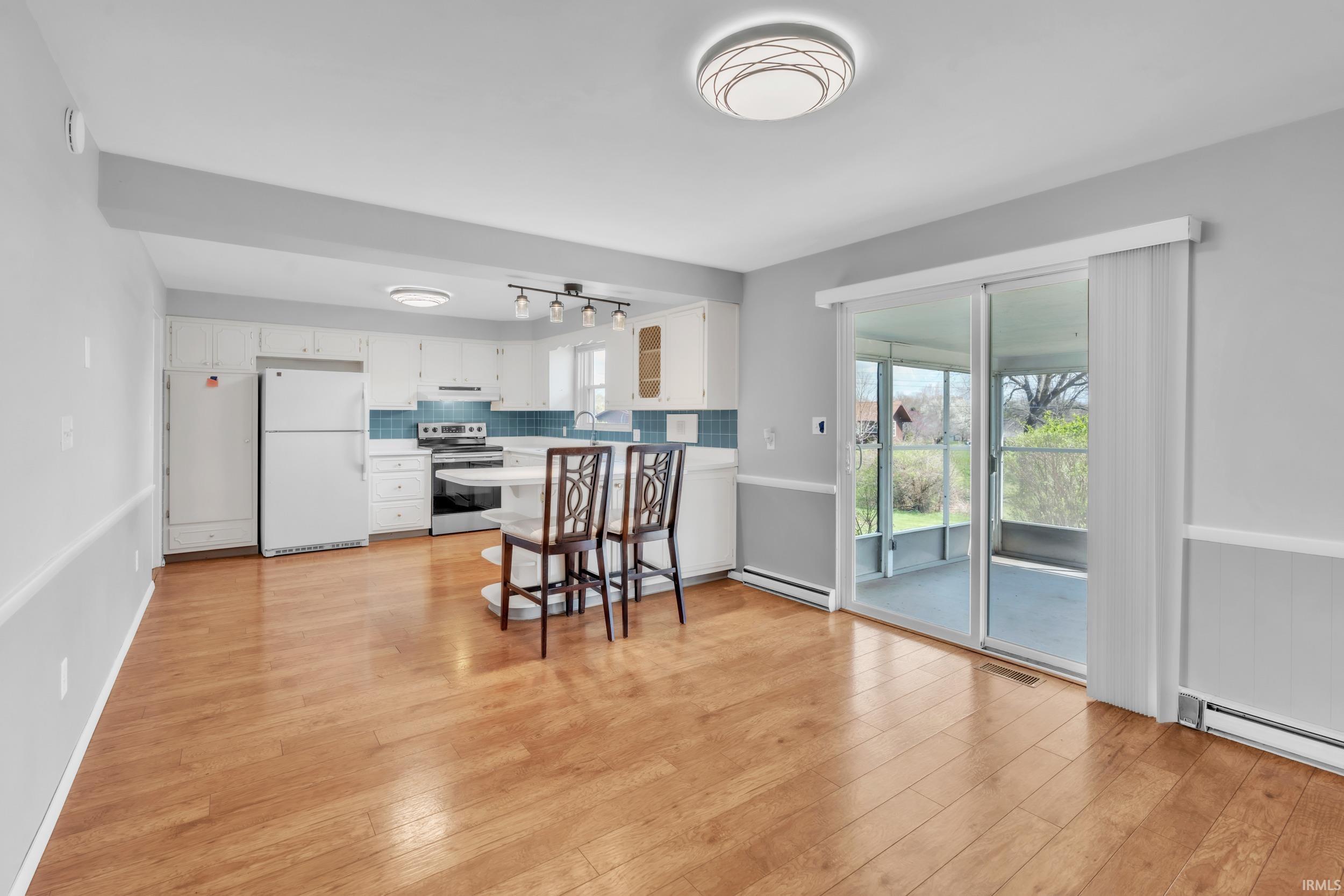 Kitchen with freestanding refrigerator, stainless steel electric stove, light countertops, white cabinets, and a peninsula