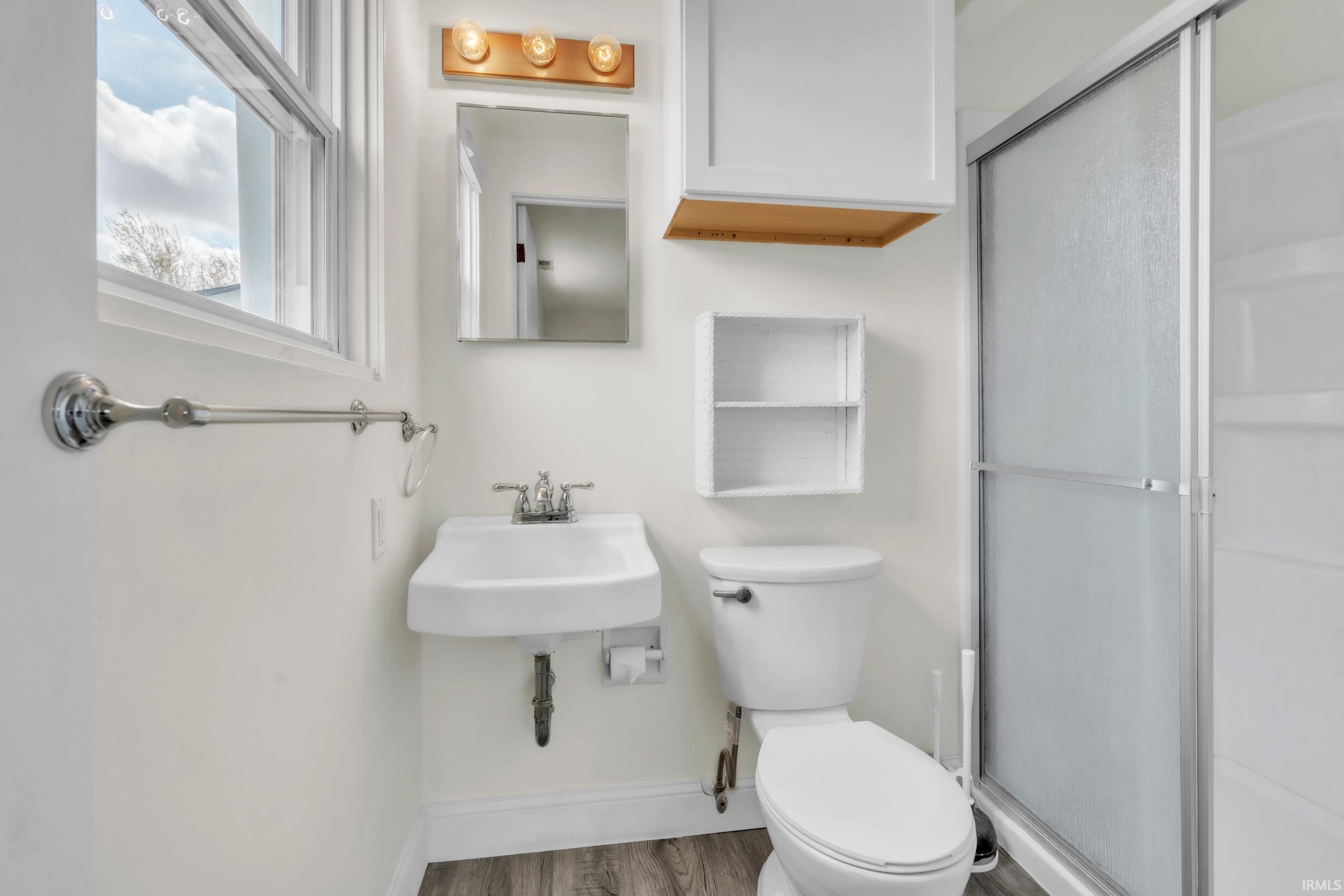 Full bath with a stall shower and light wood finished floors