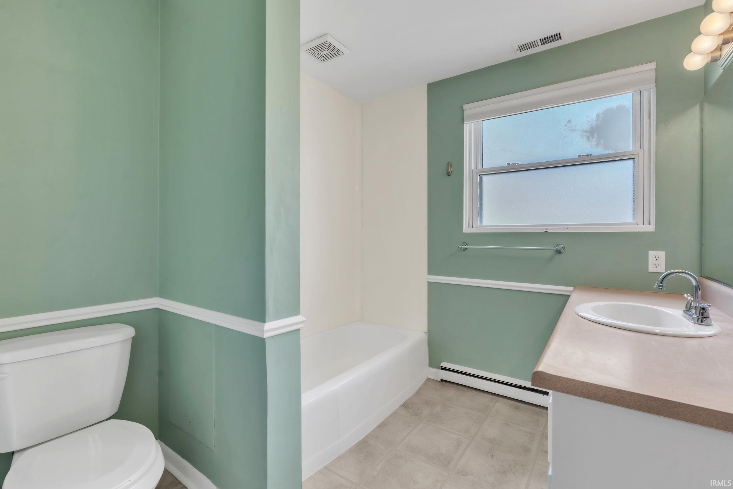 Full bath featuring vanity, baseboard heating, and a tub