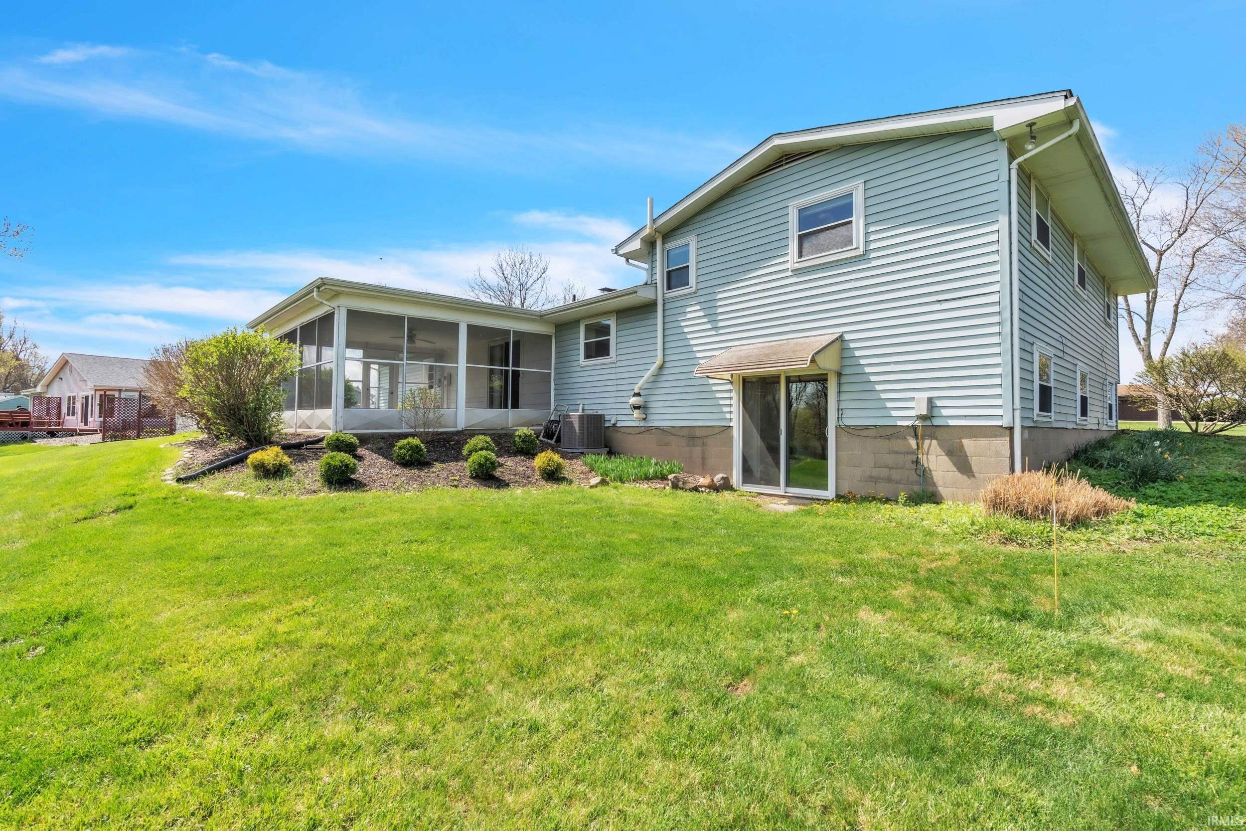 Rear view of house featuring a sunroom and a lawn