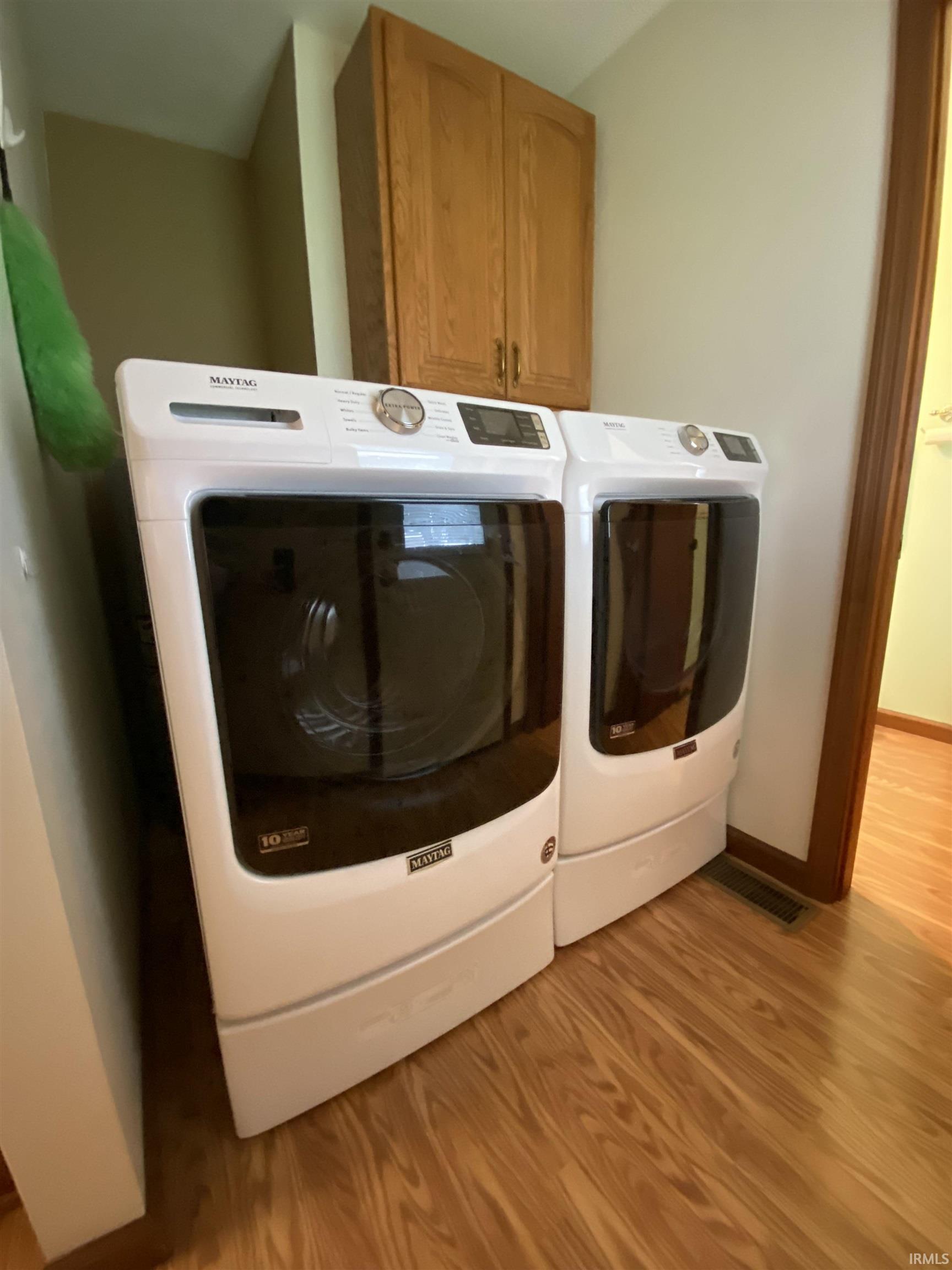 Laundry area featuring vinyl plank flooring, washing machine and dryer, and cabinet space.