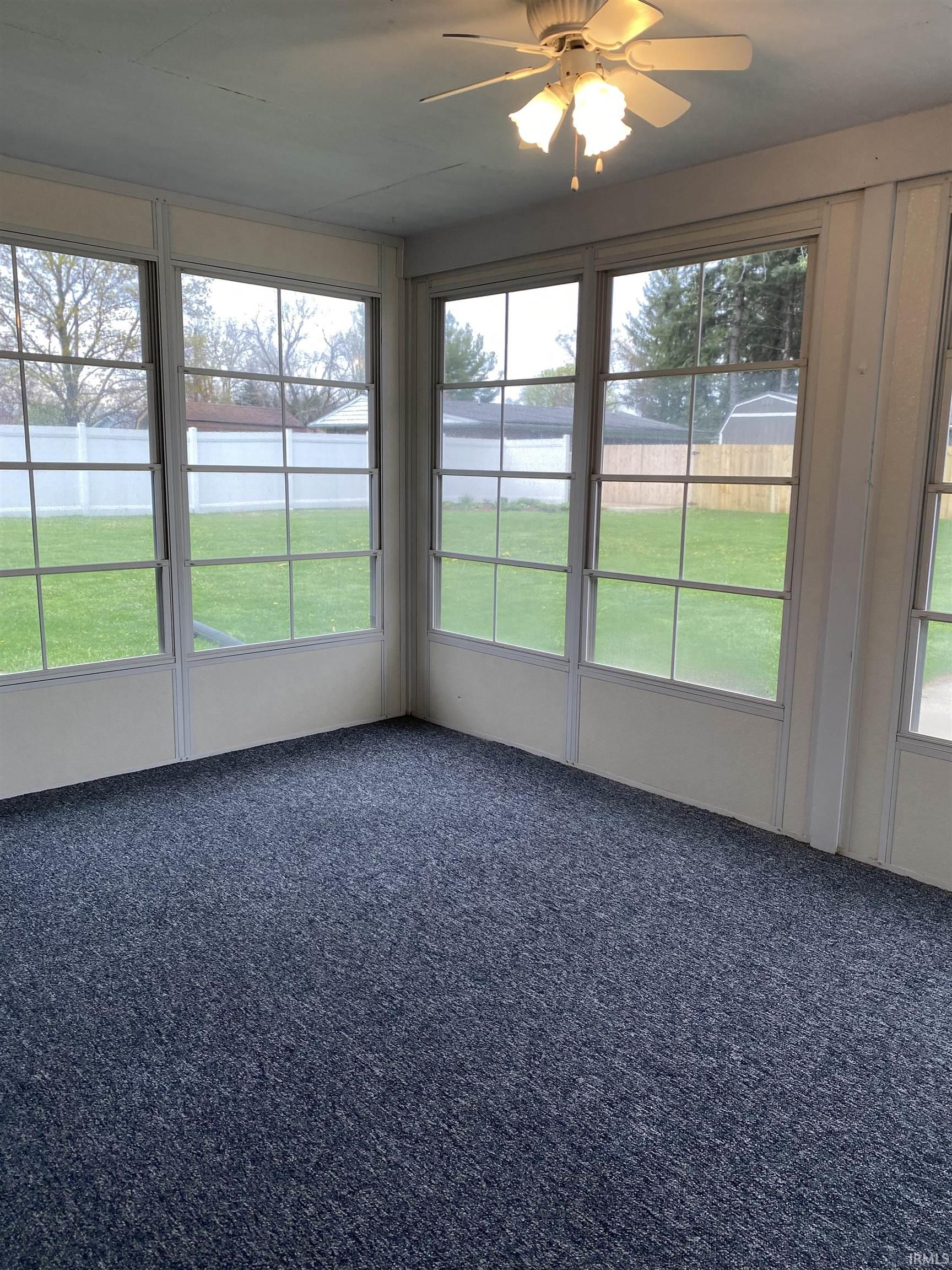 Sun room featuring a ceiling fan overlooking the back yard.