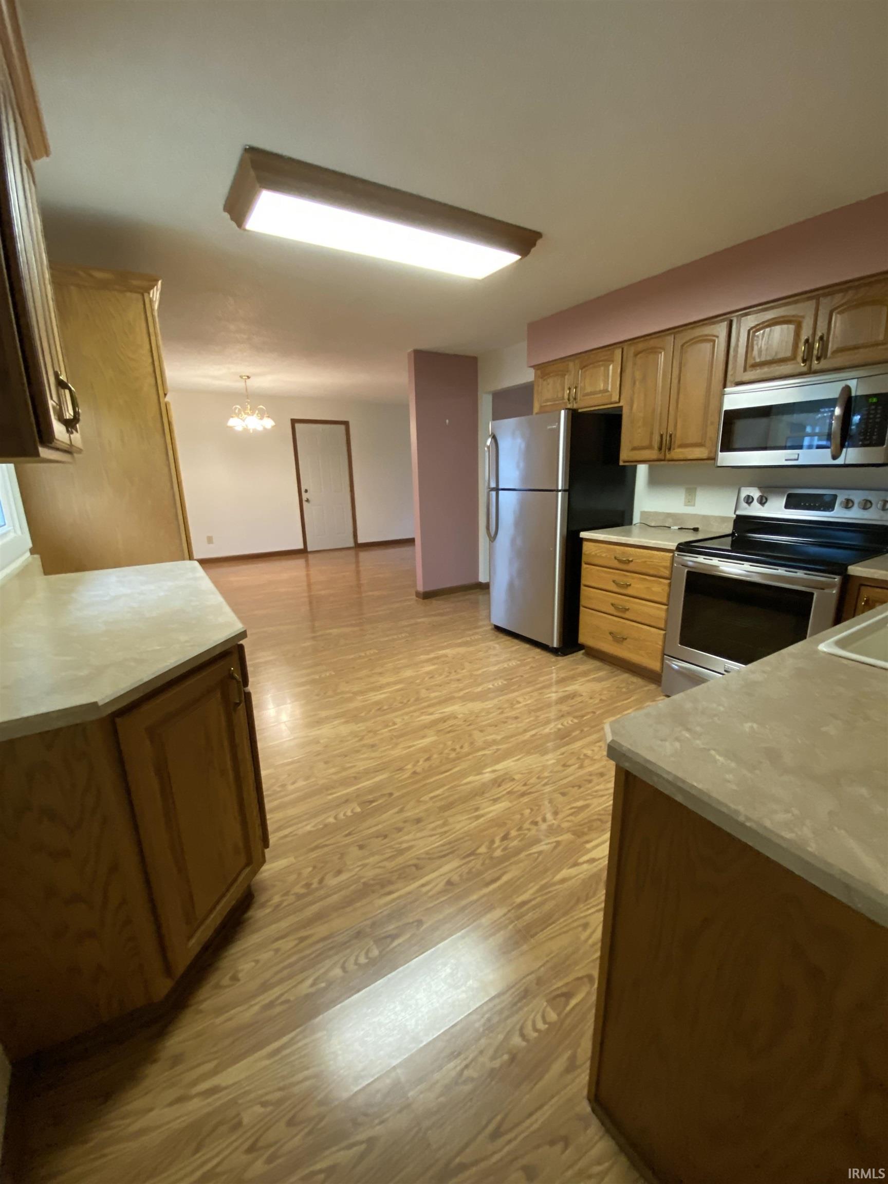 Kitchen with stainless steel appliances with vinyl plank flooring and wood finish cabinetry.