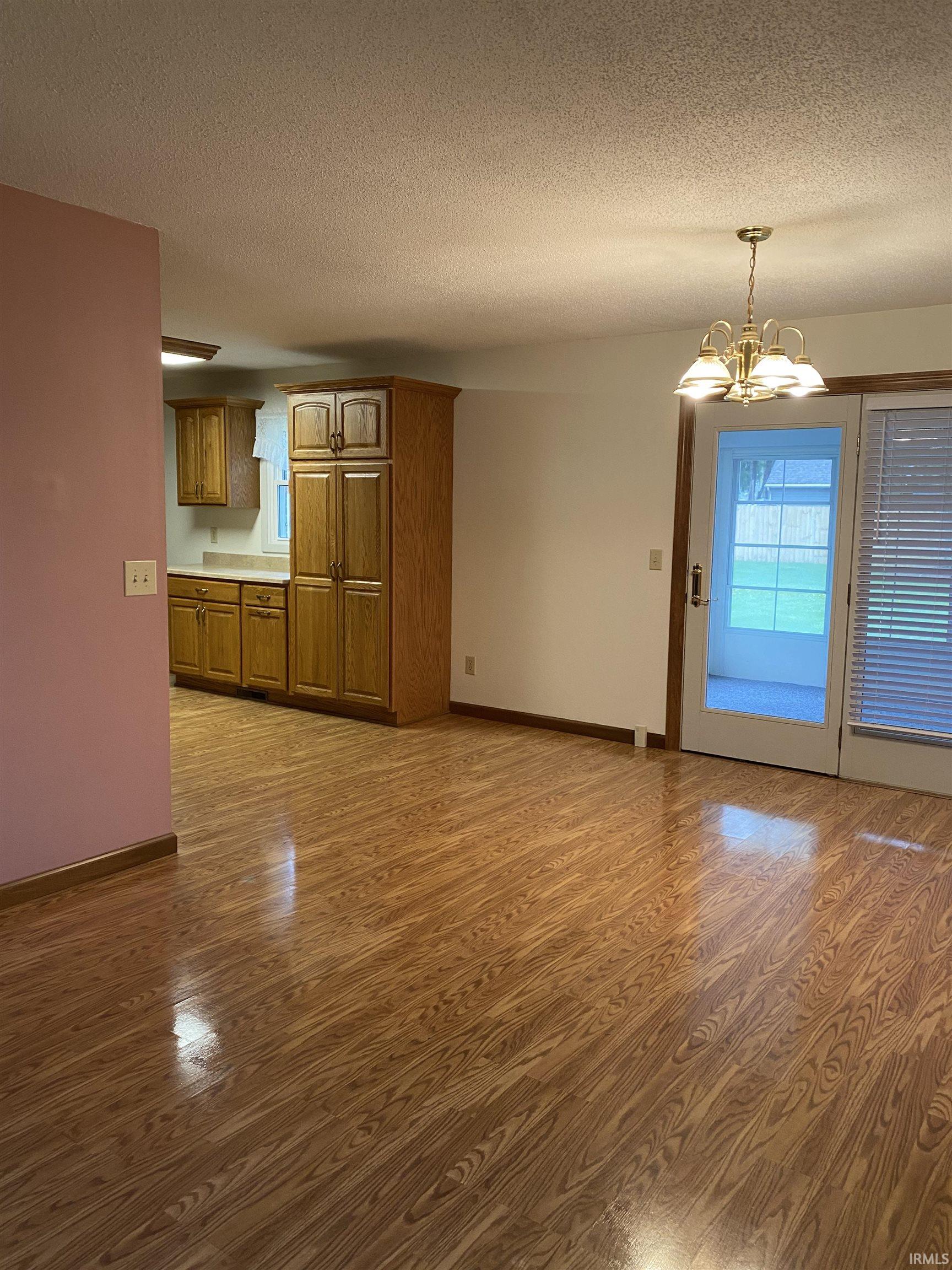 Dining area with vinyl plank flooring and a chandelier. Door goes out to sun room.