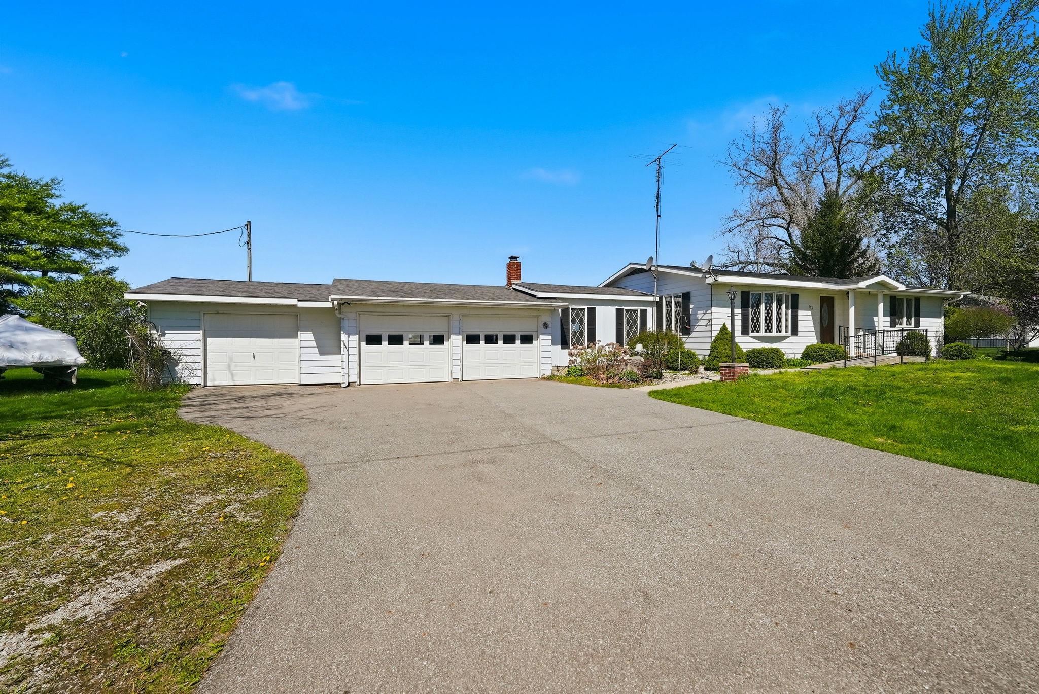Ranch-style residence featuring white siding and black shutters, with a three-car garage and an additional single-car garage