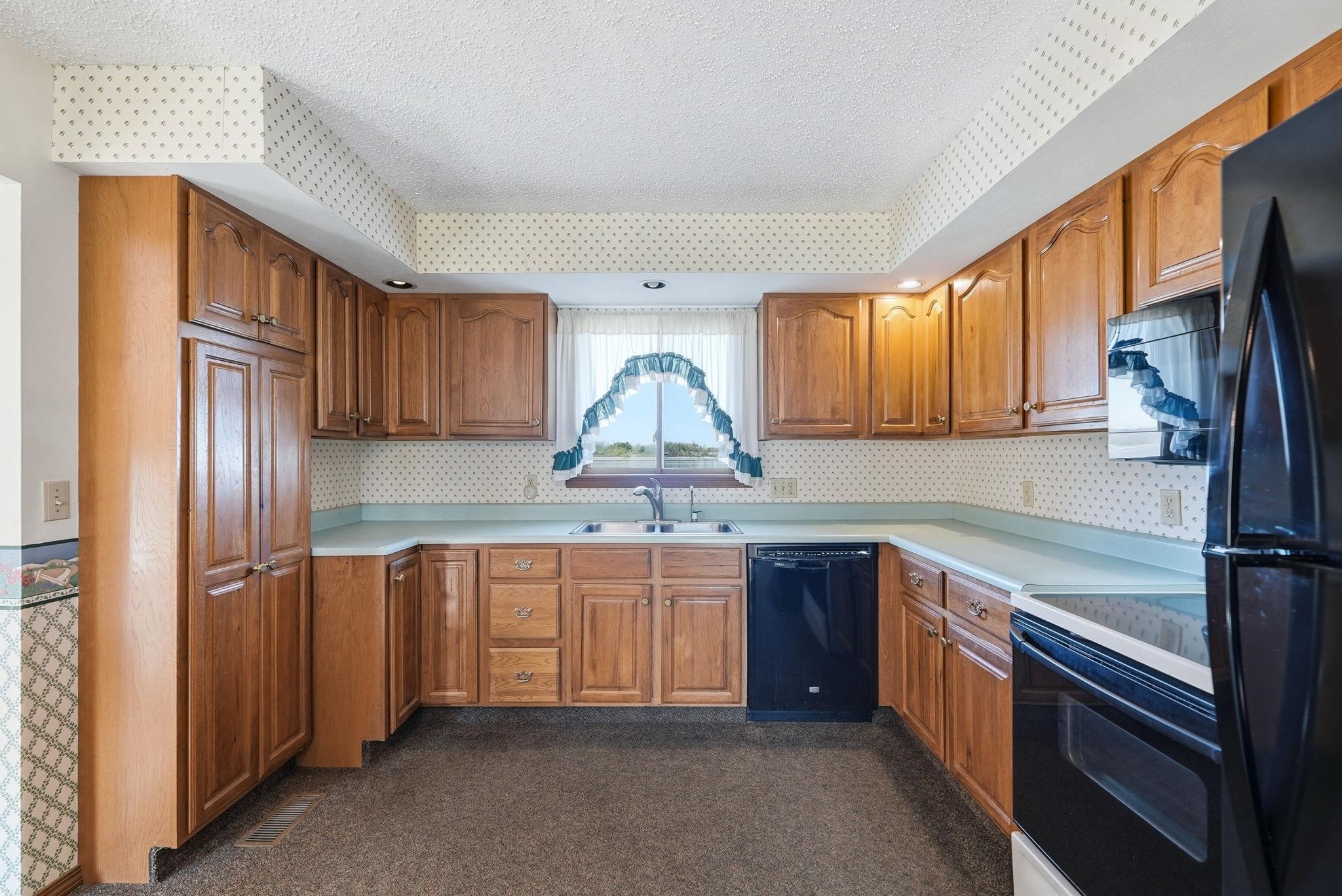 Kitchen featuring wood cabinetry, light countertops, and a window above the sink