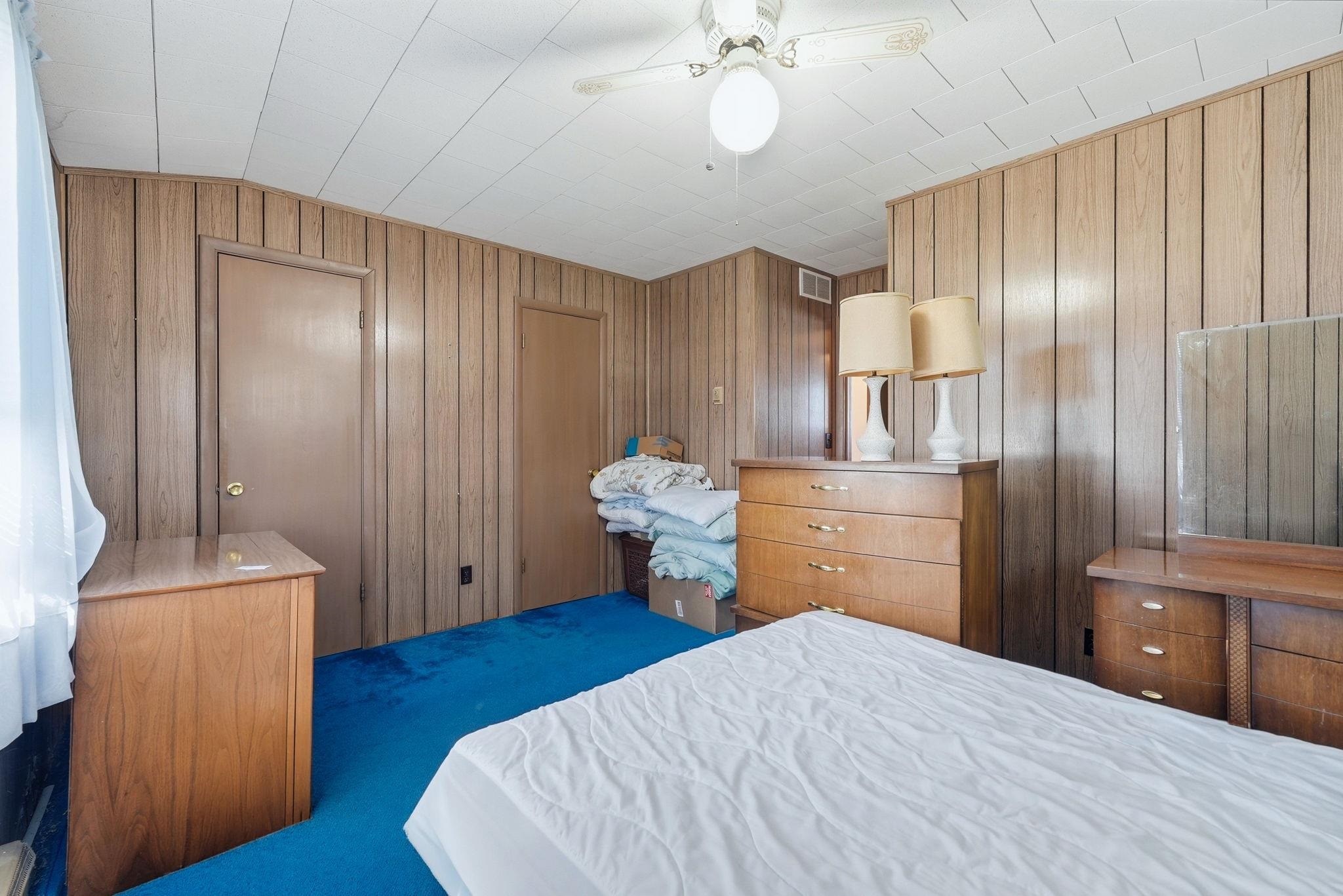 Room featuring wood-paneled walls, a textured white ceiling, and blue carpeting