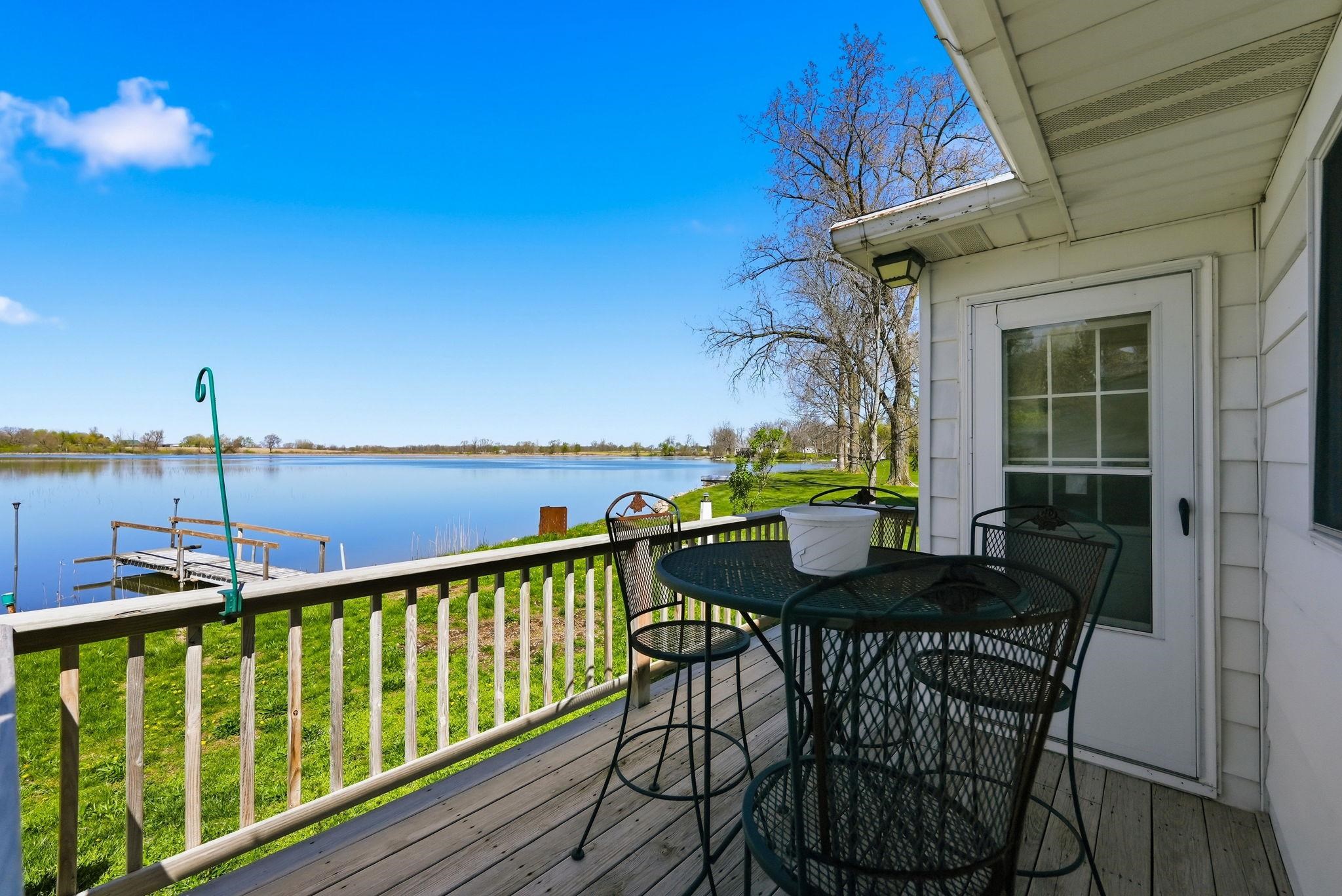 Wood deck featuring a white railing, a white exterior door with window panes, and a mounted exterior light fixture
