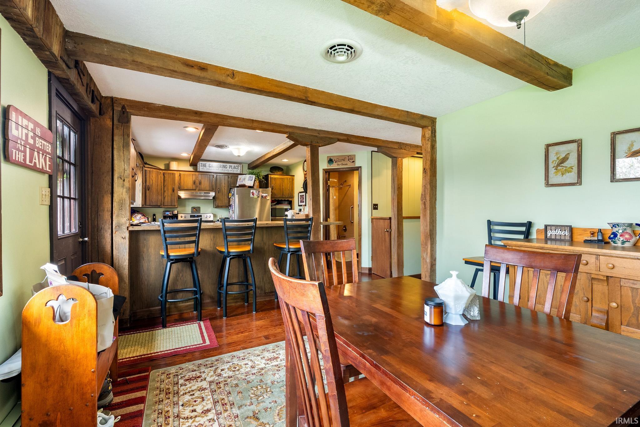 Dining area with beam ceiling and dark wood-style floors