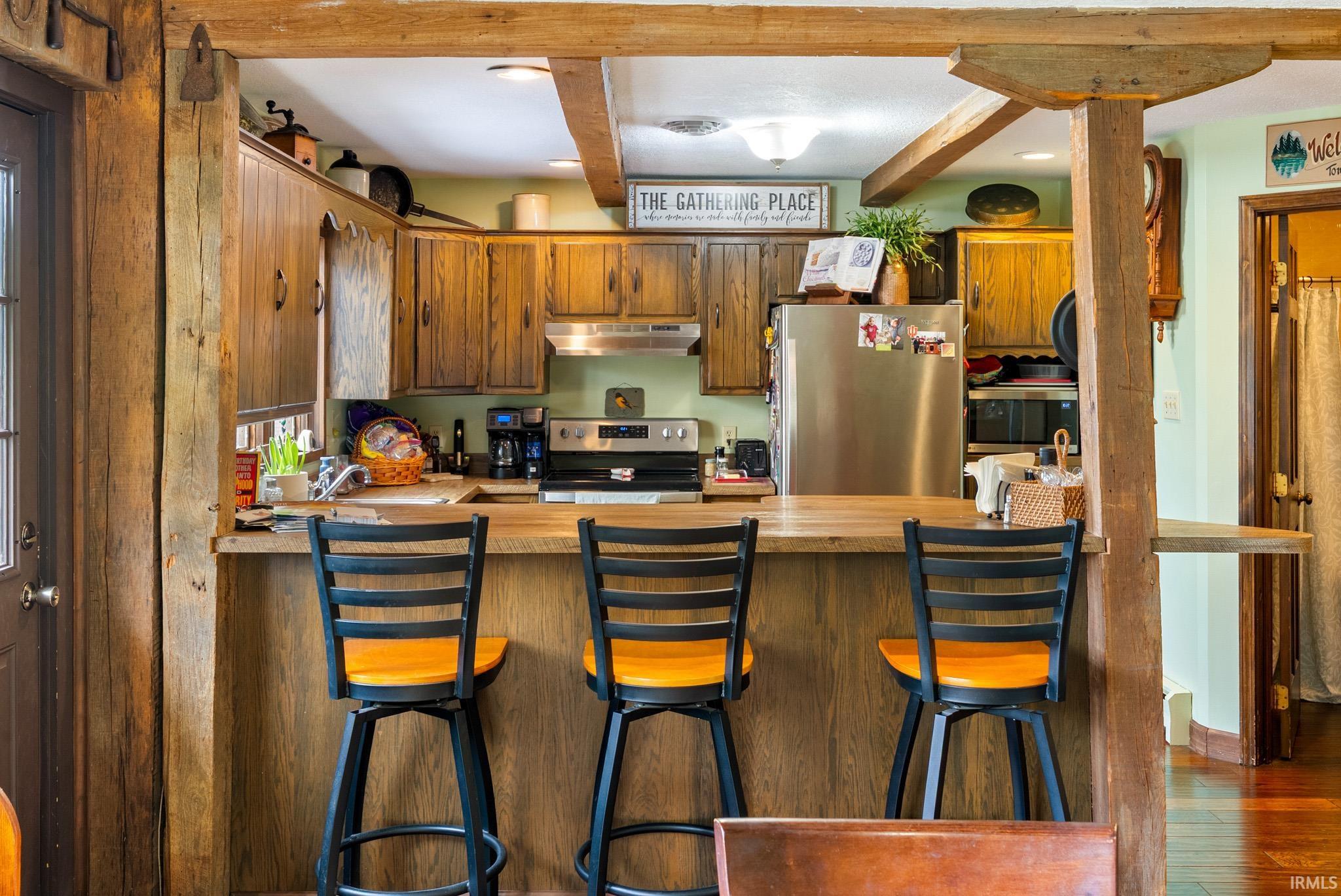 Kitchen with stainless steel appliances, a peninsula, wood finish cabinets, recessed lighting, and a kitchen bar