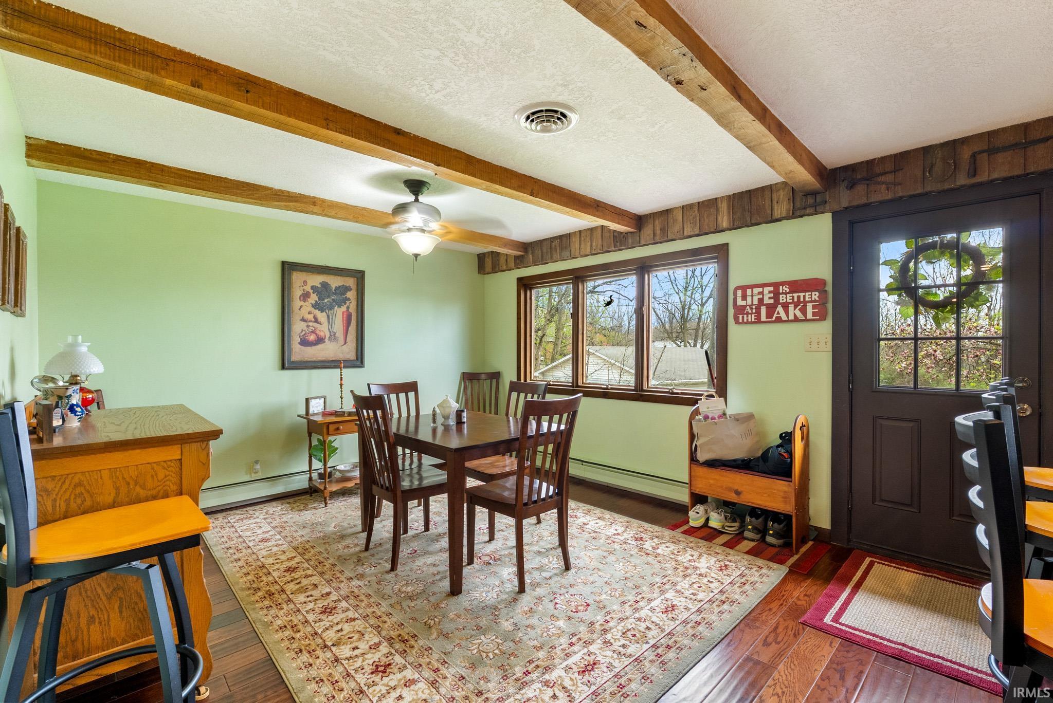 Dining space with a textured ceiling, dark wood-style floors, ceiling fan, beam ceiling, and a baseboard radiator