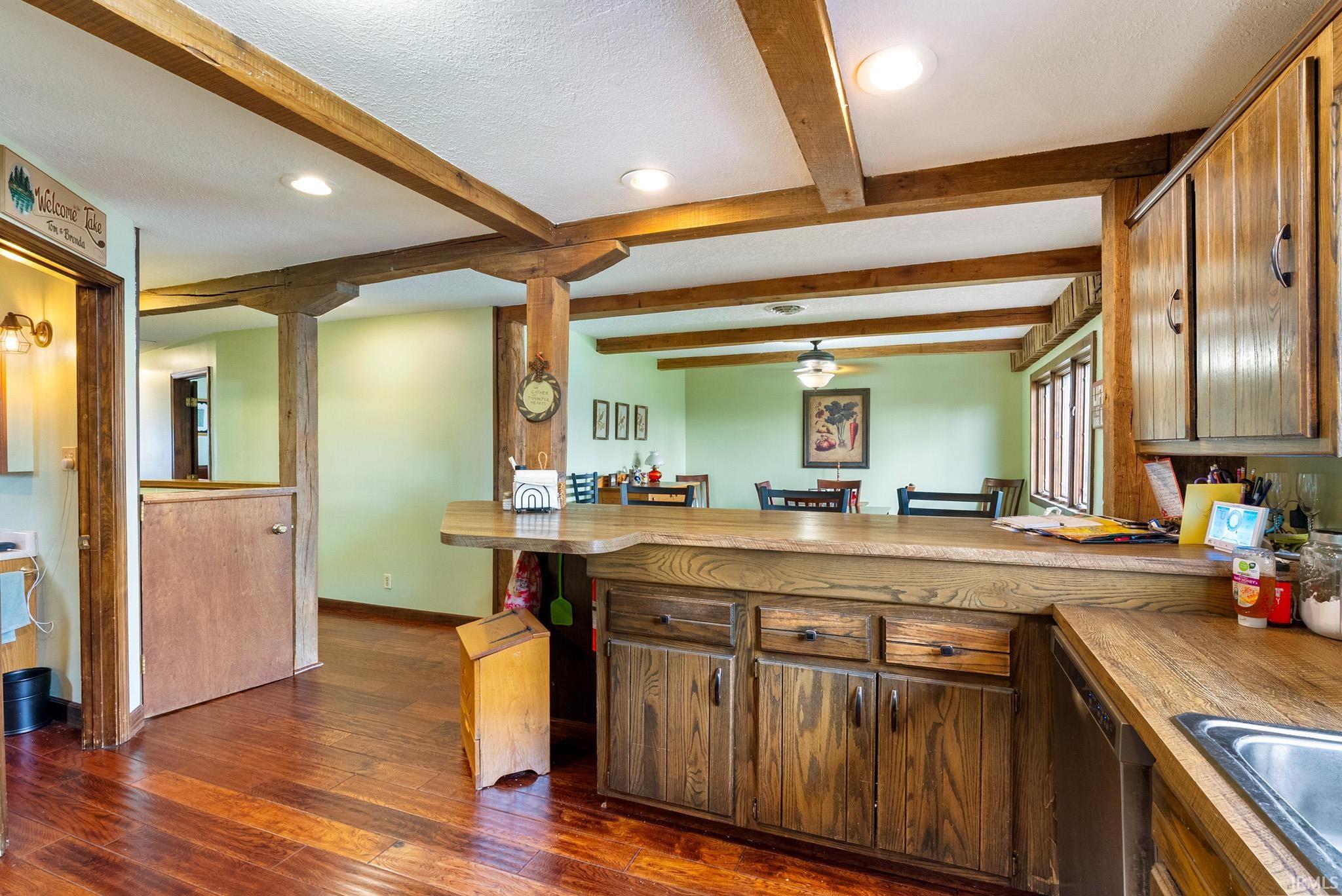 Kitchen featuring a peninsula, dark wood-style floors, recessed lighting, dishwasher, and a breakfast bar area