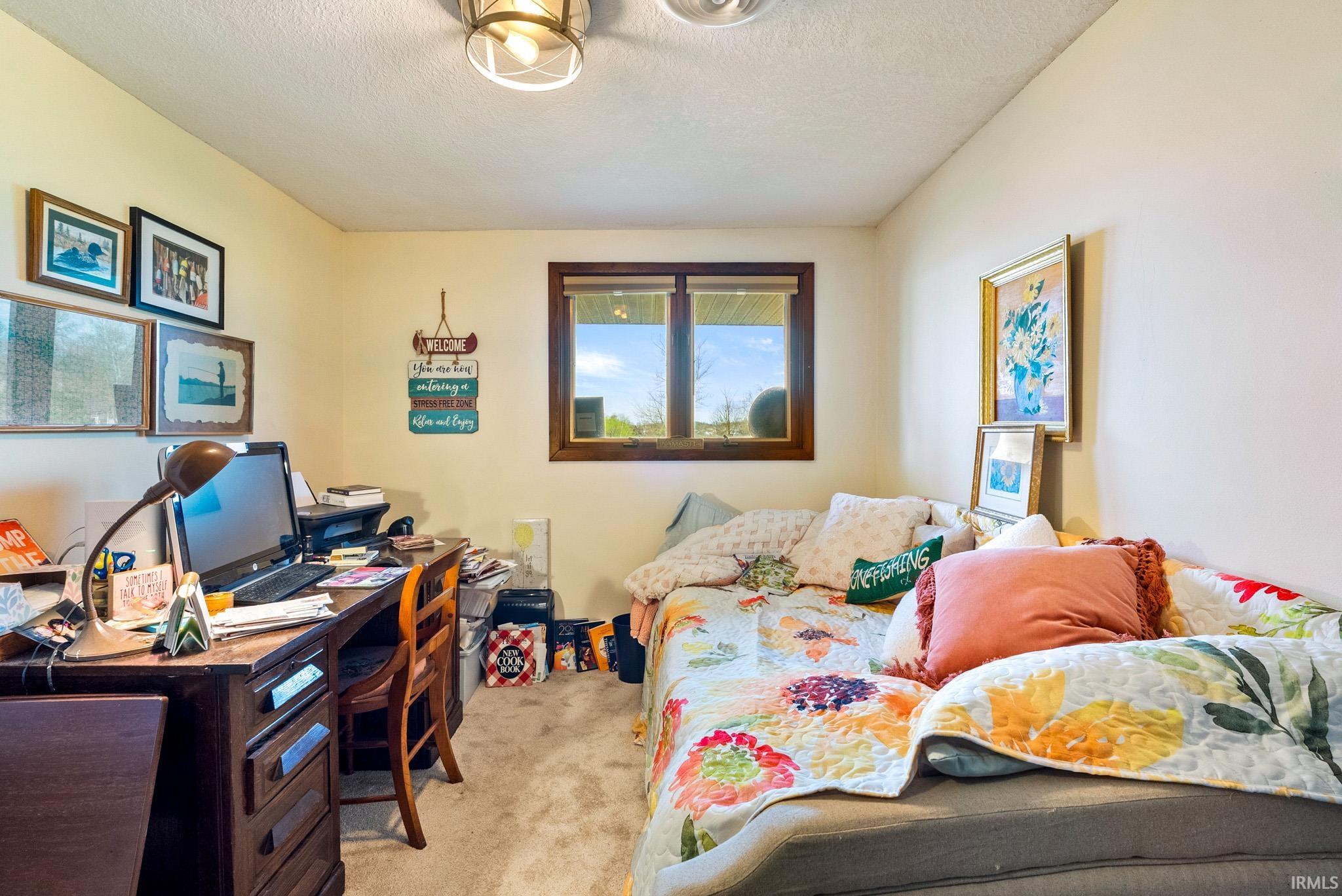Bedroom featuring light carpet, a desk, and a textured ceiling
