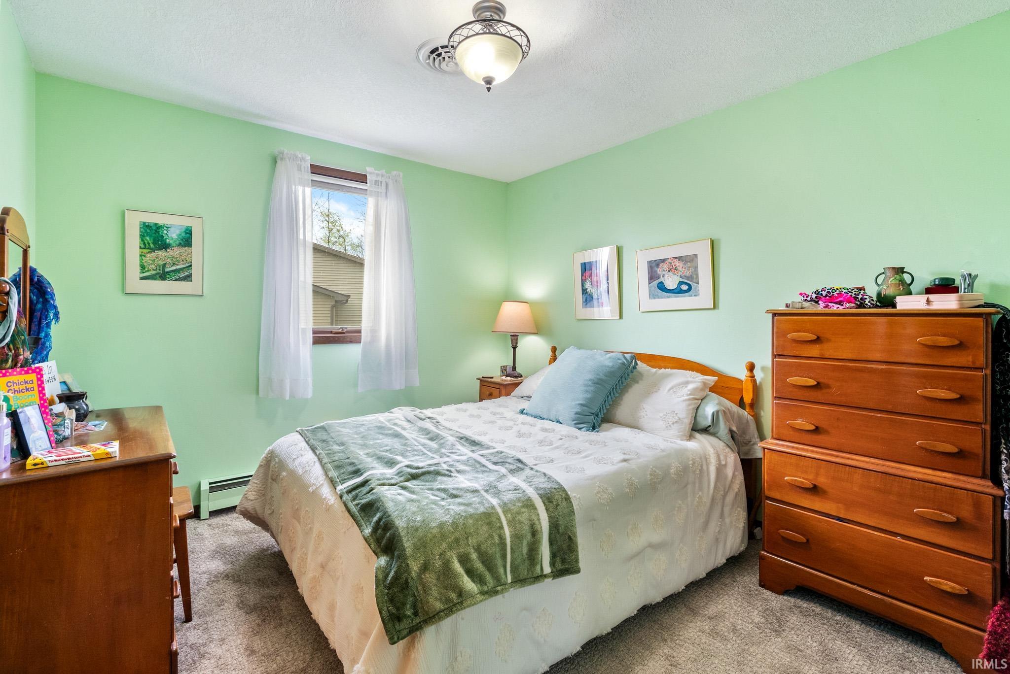 Carpeted bedroom featuring a baseboard heating unit