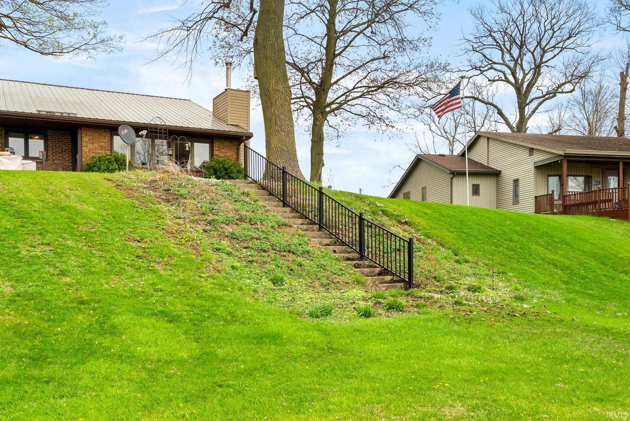View of side of property featuring a chimney, brick siding, a metal roof, and a yard