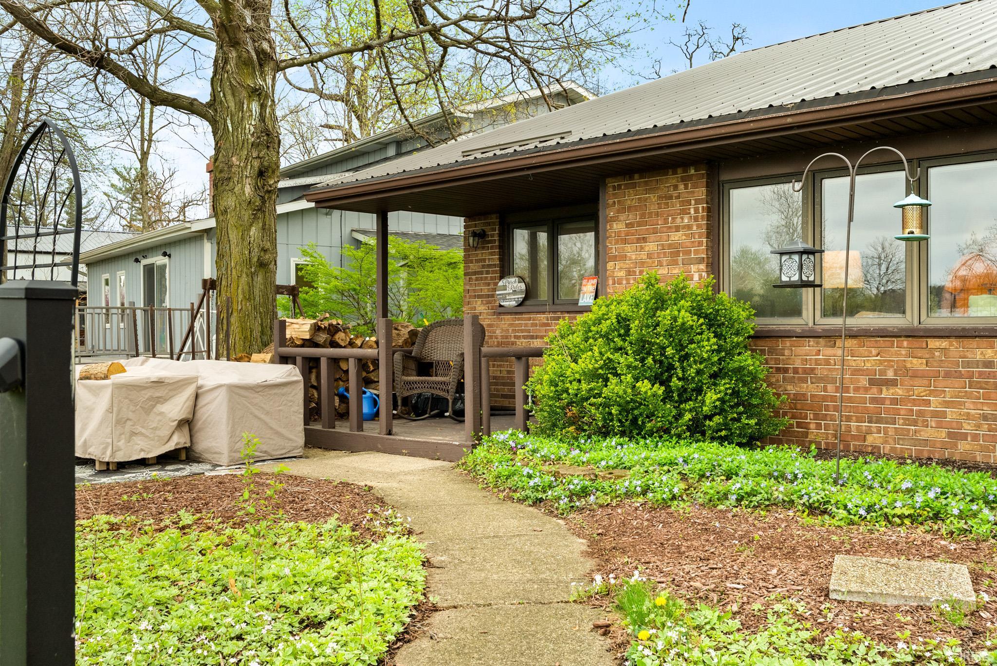 Exterior space with brick siding, a metal roof, and a deck