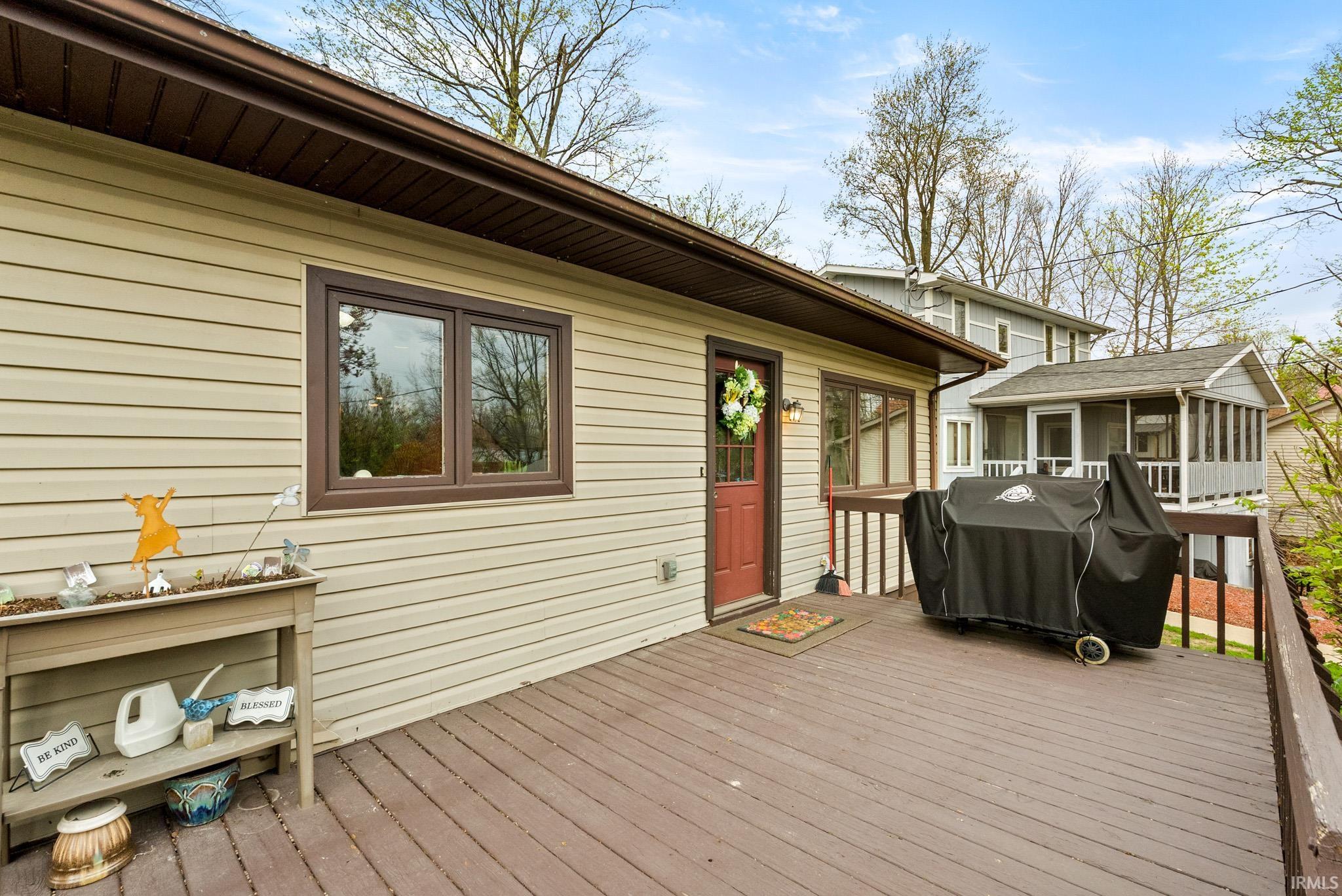 Wooden deck featuring area for grilling and a sunroom