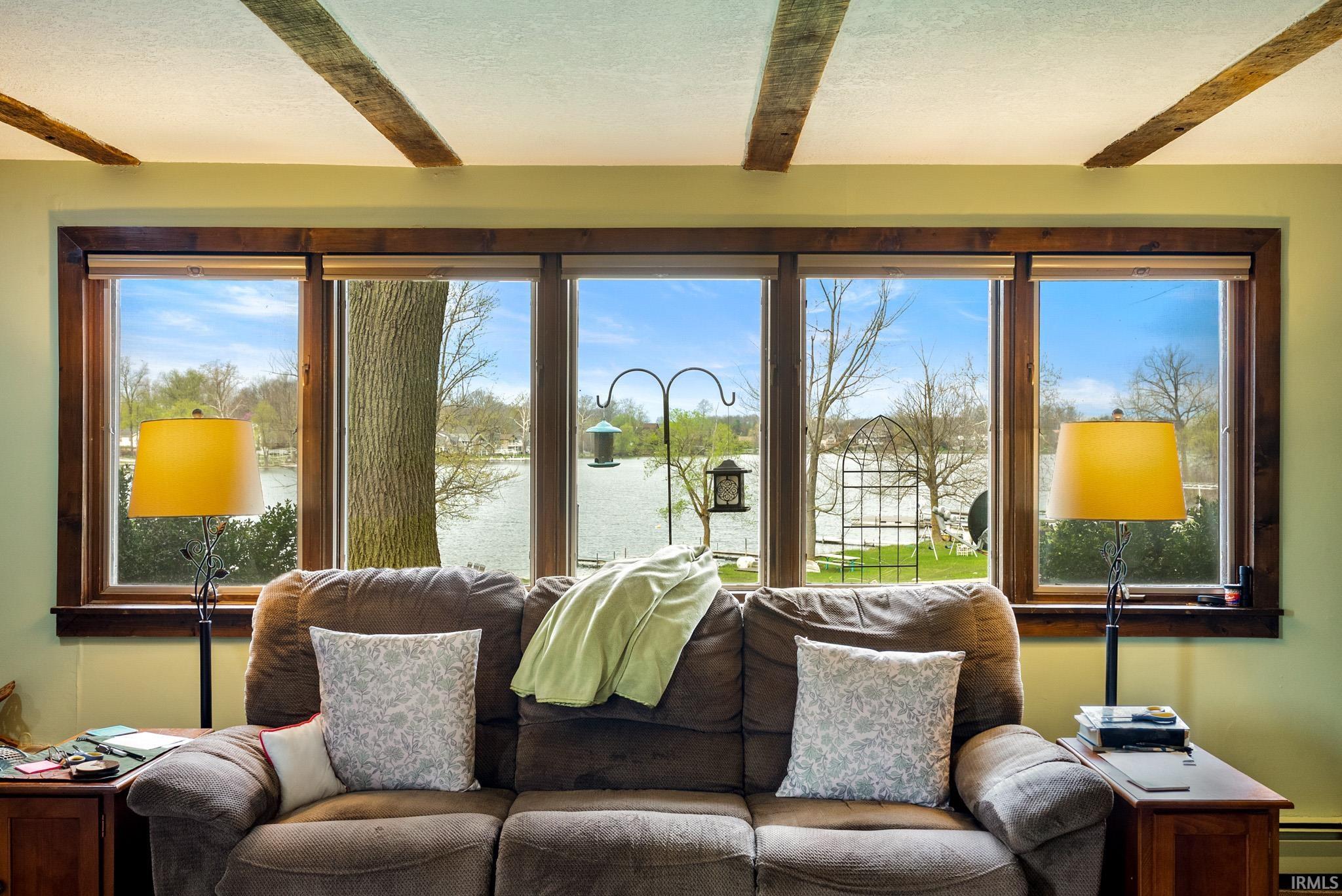 Sunroom featuring healthy amount of natural light, a water view, beam ceiling, and baseboard heating