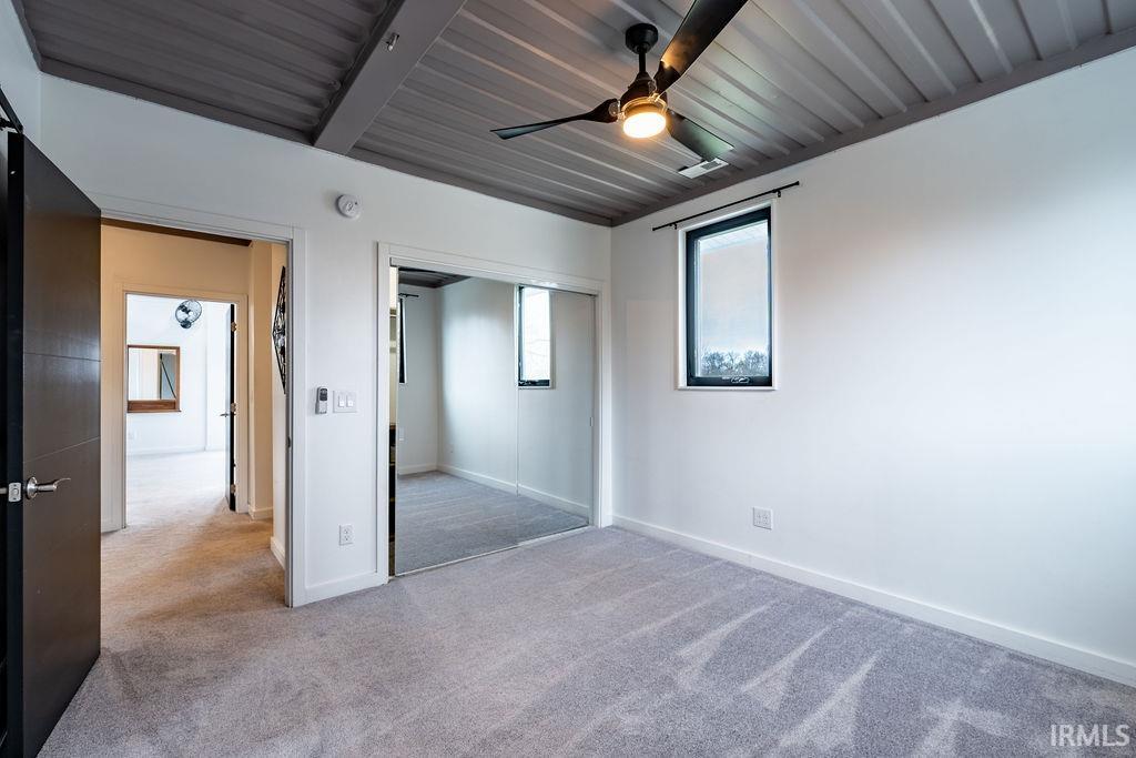 Unfurnished bedroom featuring a closet, light carpet, and a ceiling fan