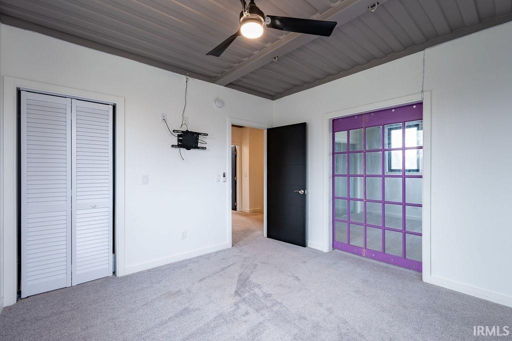 Unfurnished bedroom featuring light carpet, ceiling fan, and a closet