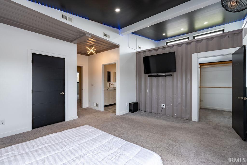 Unfurnished bedroom with carpet floors, a walk in closet, and ensuite bath