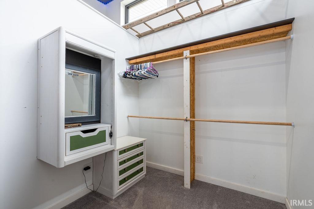 Walk in closet with dark colored carpet
