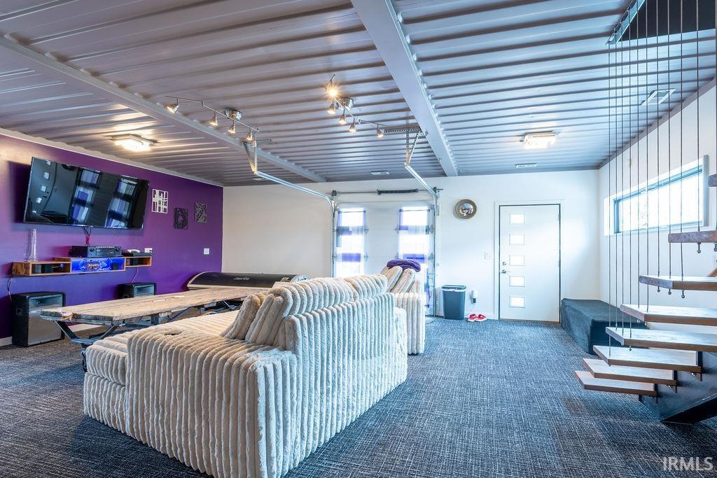 Cinema room featuring dark carpet, healthy amount of natural light, and a garage