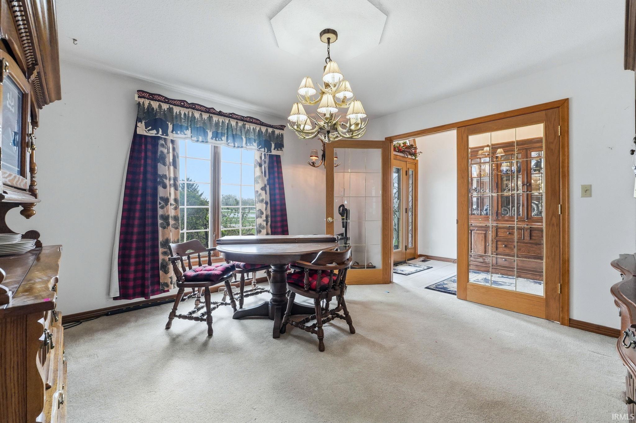 Carpeted dining space with hanging lights and baseboards
