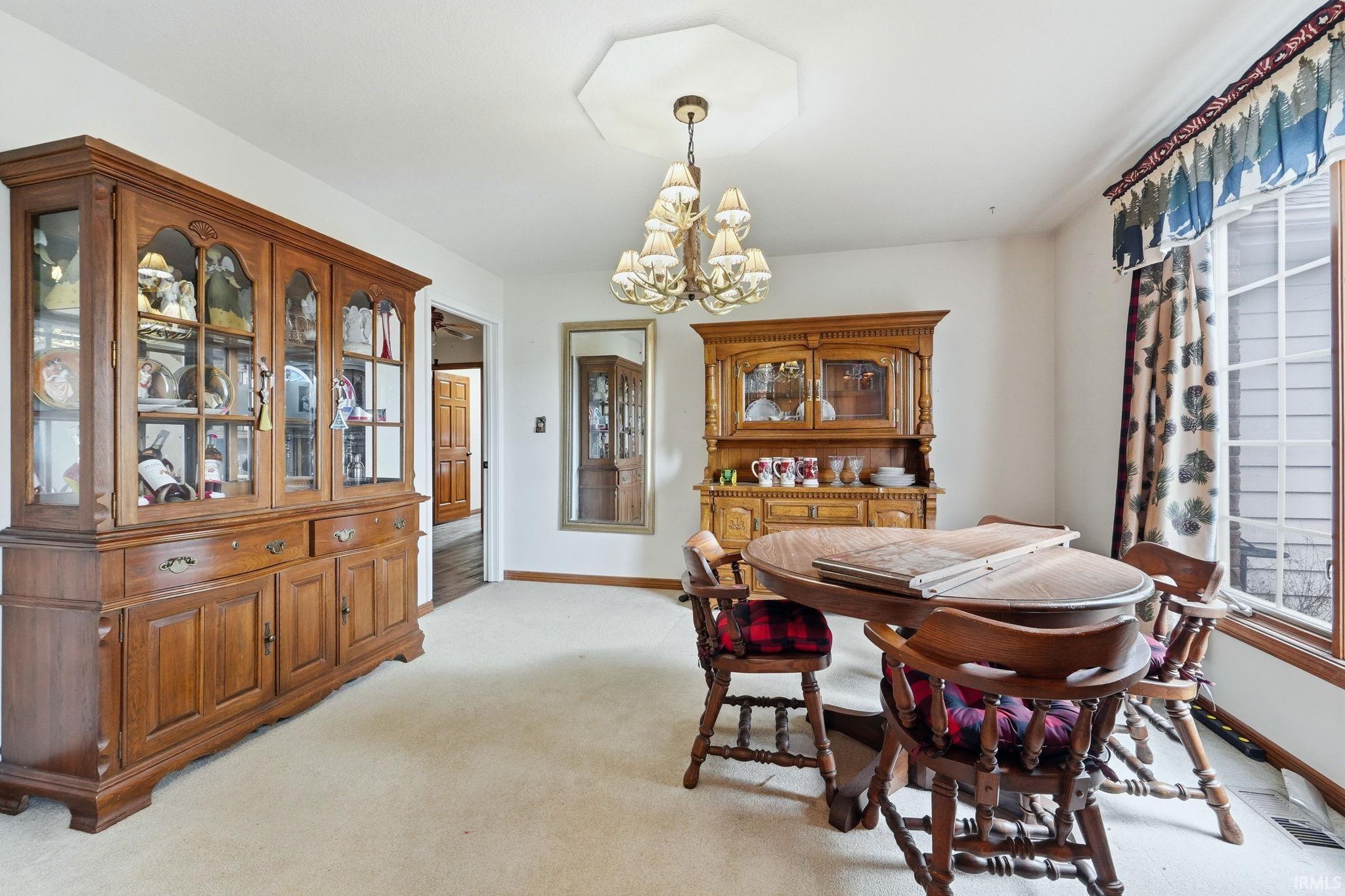 Dining room with suspended lighting and light colored carpet