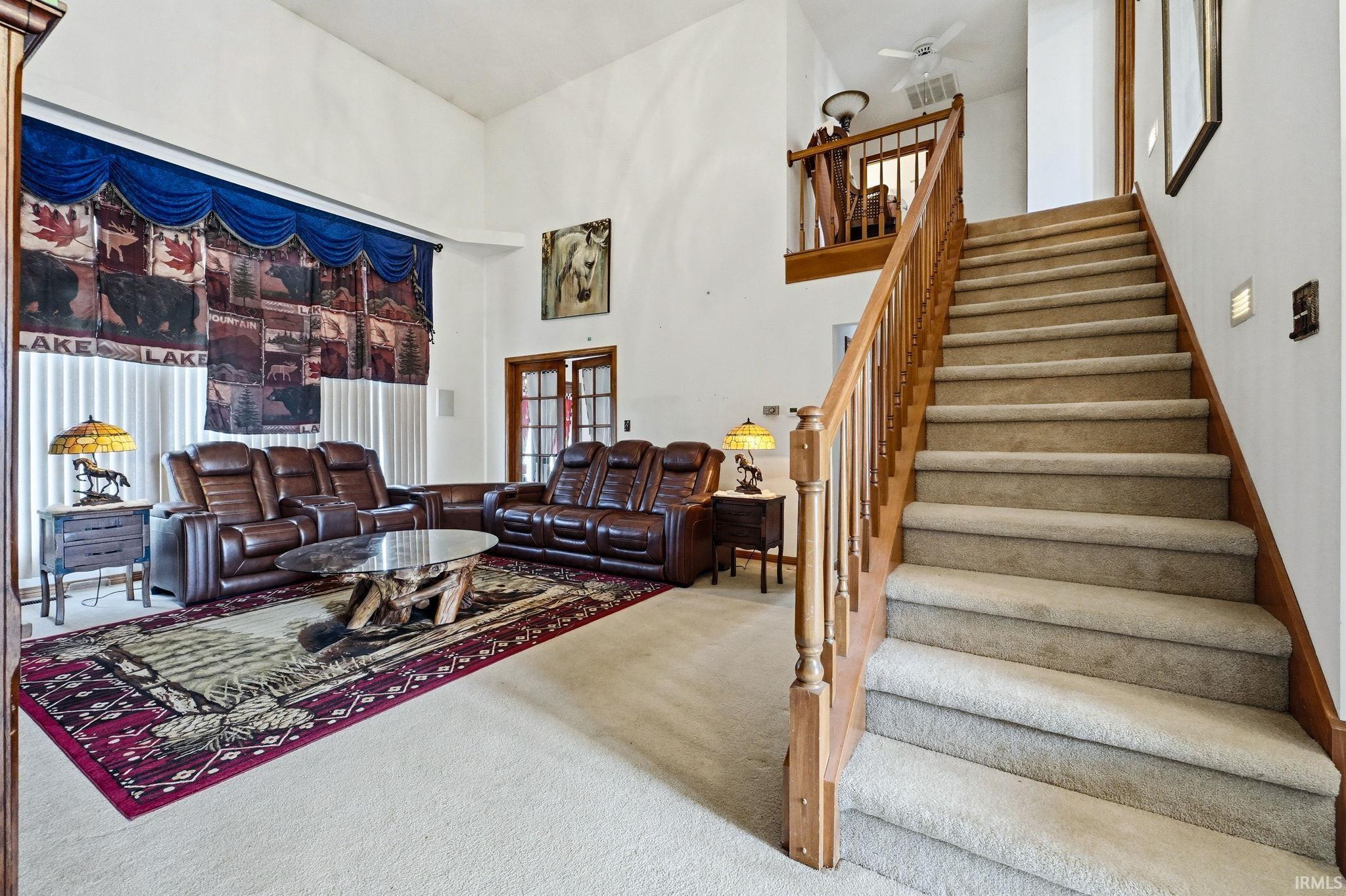 Living room with carpet flooring, a high ceiling, and plenty of natural light