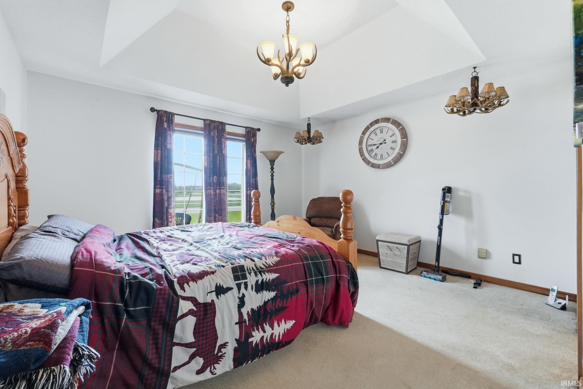 Bedroom featuring hanging lights, carpet floors, and a tray ceiling