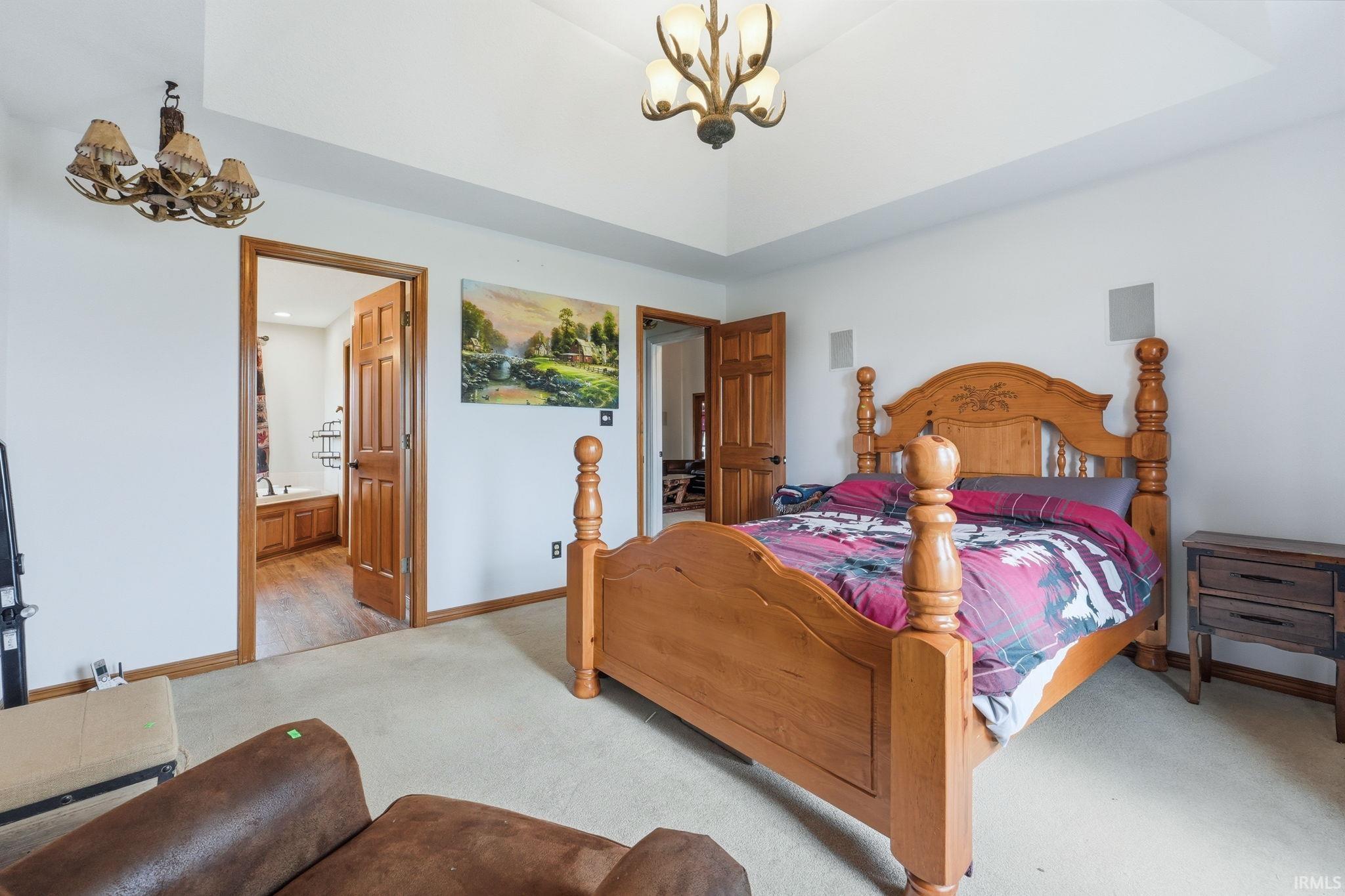 Bedroom featuring suspended lighting, carpet, and connected bathroom