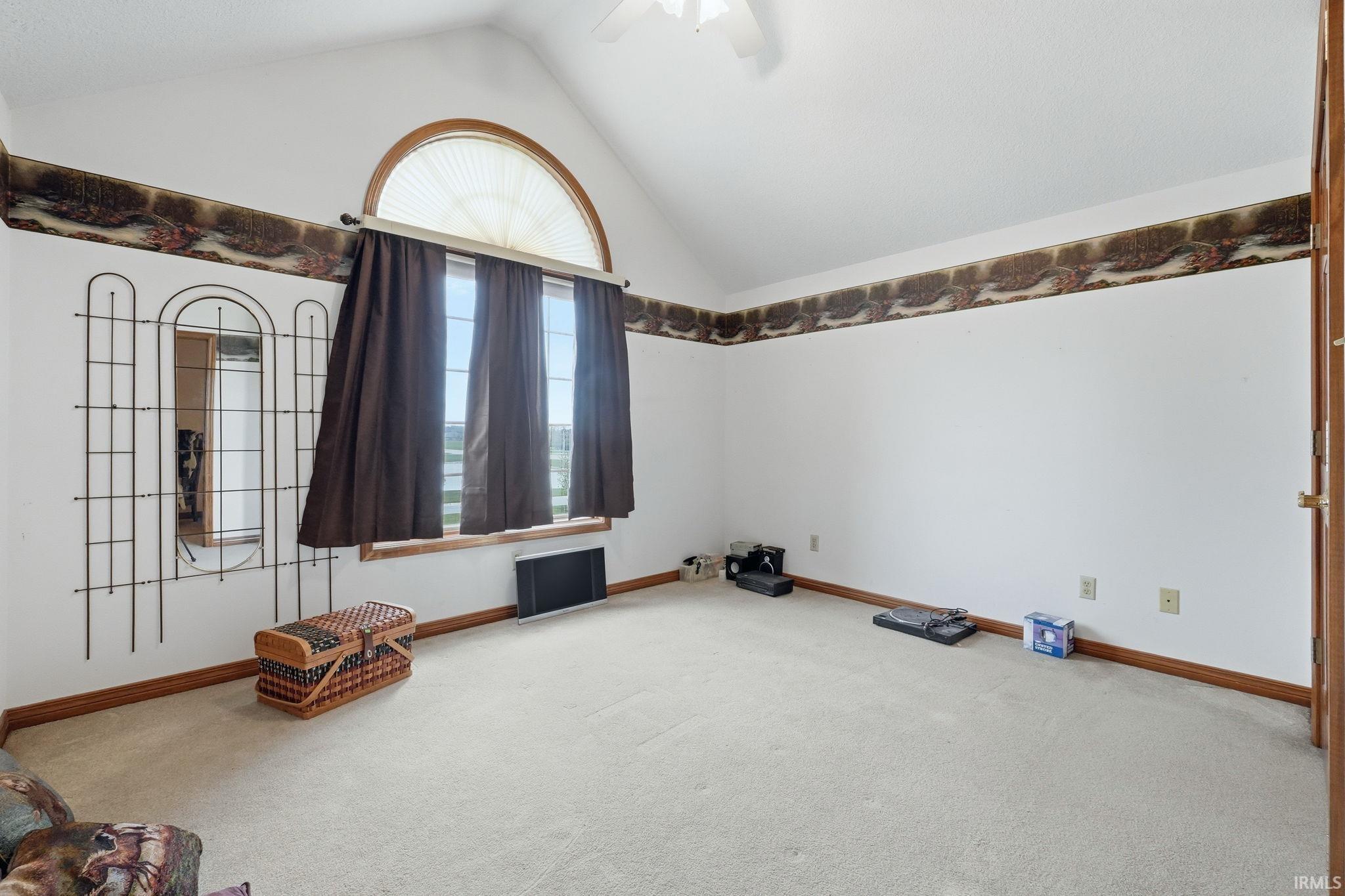 Carpeted spare room featuring a high ceiling and a ceiling fan