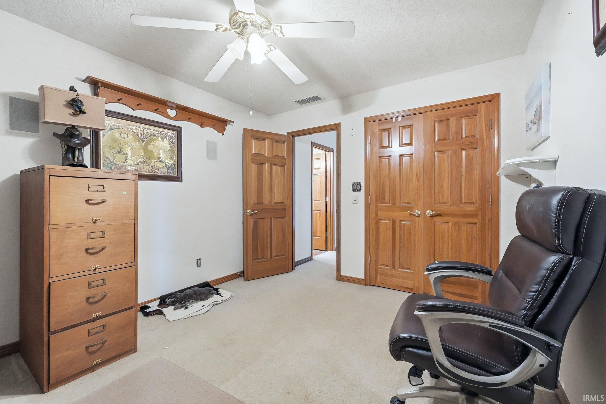 Office with ceiling fan and light carpet