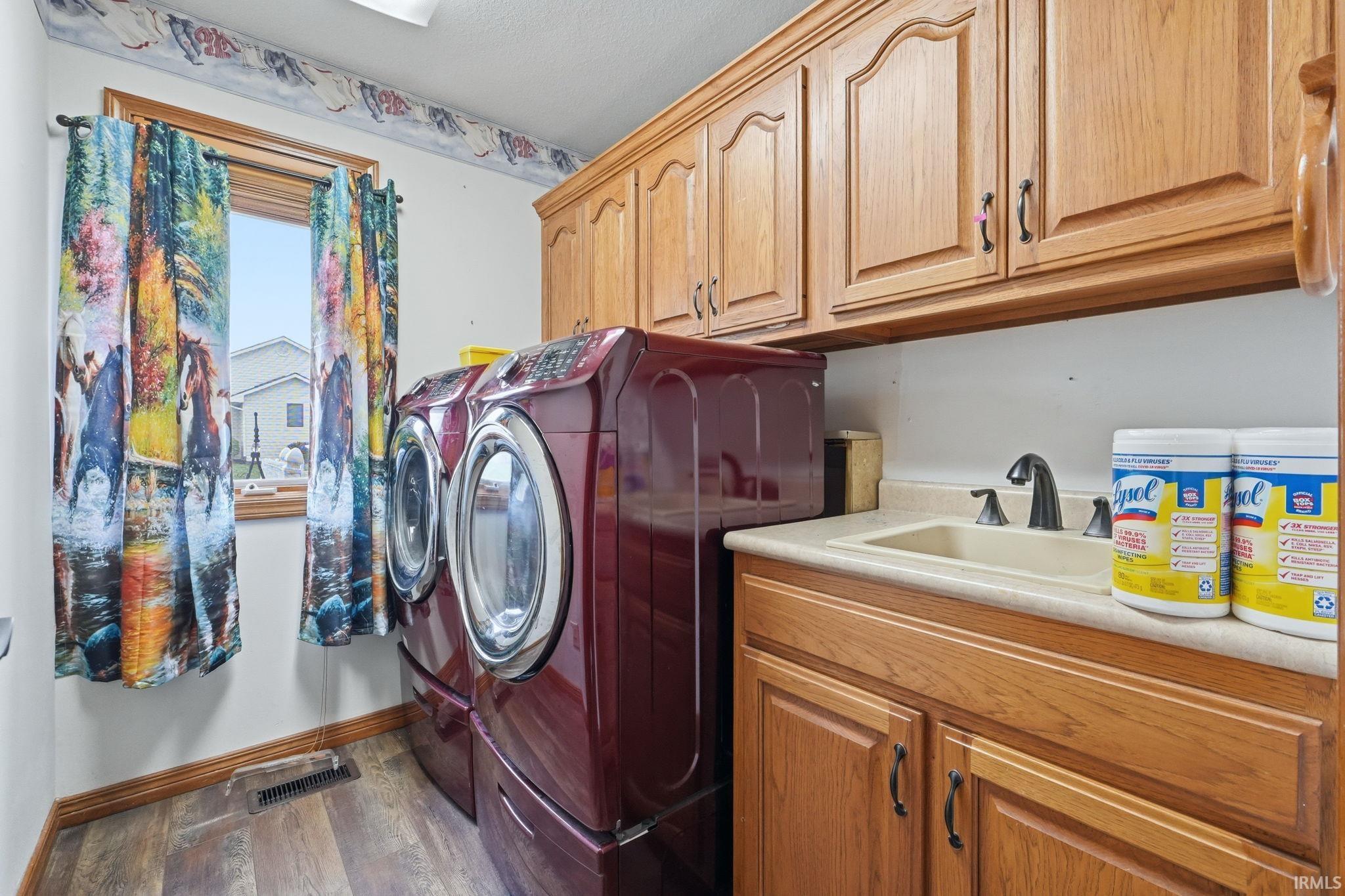 Laundry room featuring cabinet space, washing machine and clothes dryer, and dark wood-type flooring