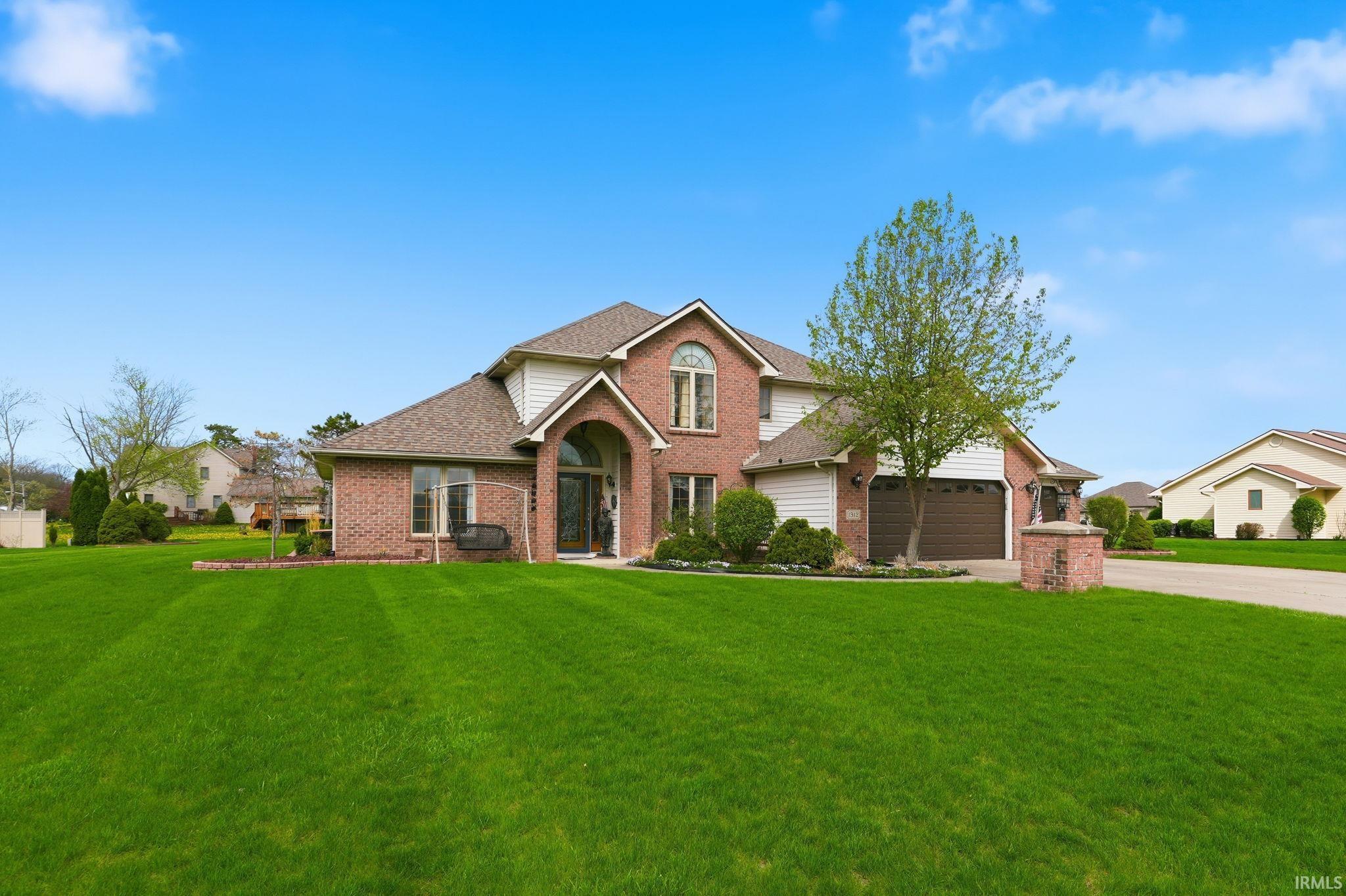View of front of house featuring brick siding, a front yard, roof with shingles, and concrete driveway